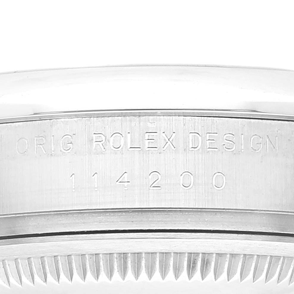 This image shows a close-up of the side case of a Rolex Oyster Perpetual 114200 Men's Stainless Steel White Dial 114200 Men's Stainless Steel White Dial watch, featuring its engraved model number.