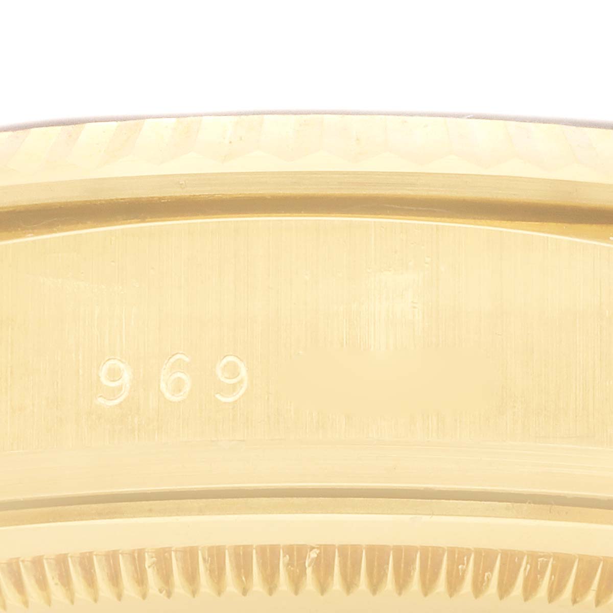 The image shows a close-up of a part of the Rolex President 18038 Men
s Yellow Gold Champagne Dial watch, highlighting its fluted bezel and engraved numbers.