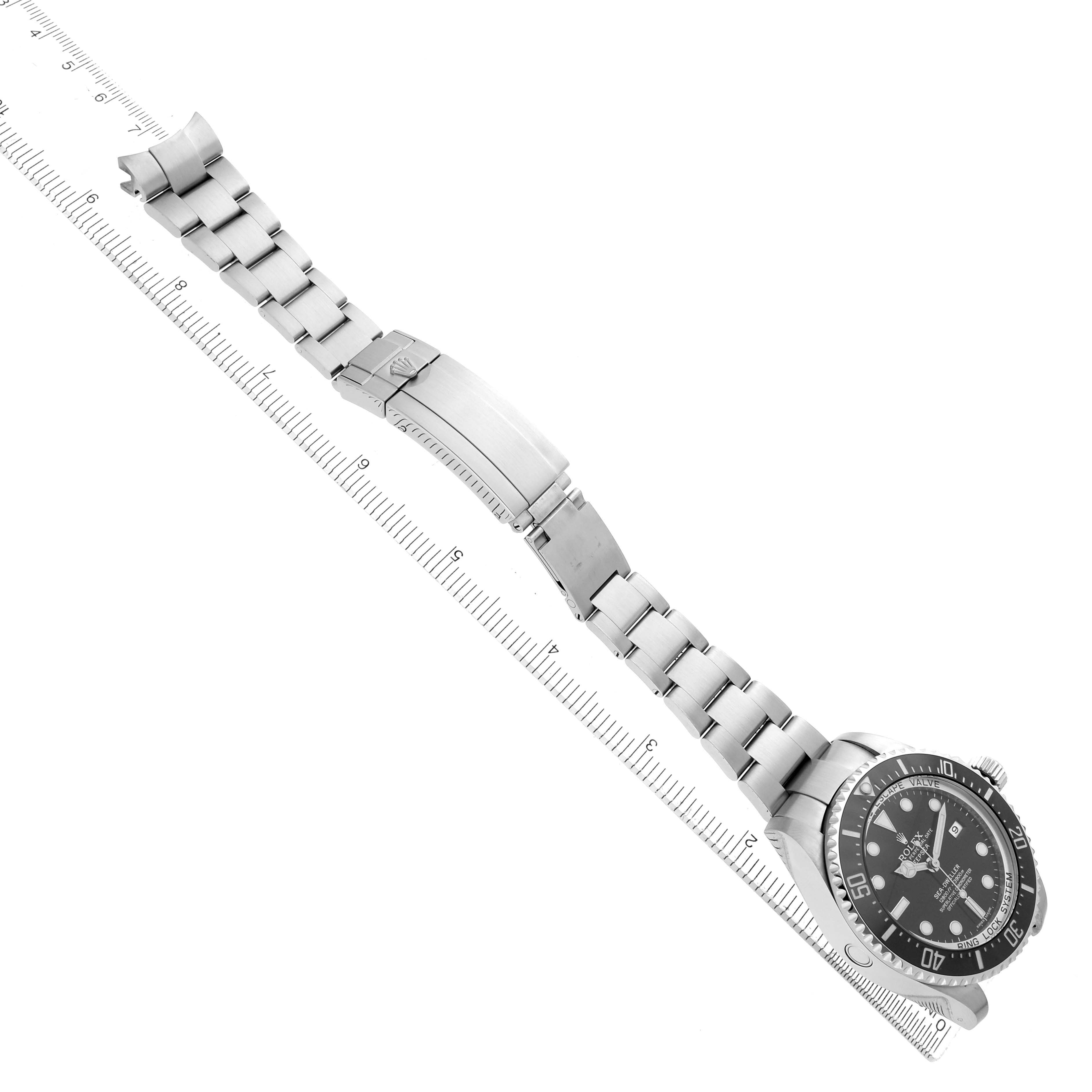 The Rolex Sea-Dweller 116660 Men
s Stainless Steel Black Dial watch is shown at an angled view, displaying the bracelet, clasp, and face alongside a ruler.