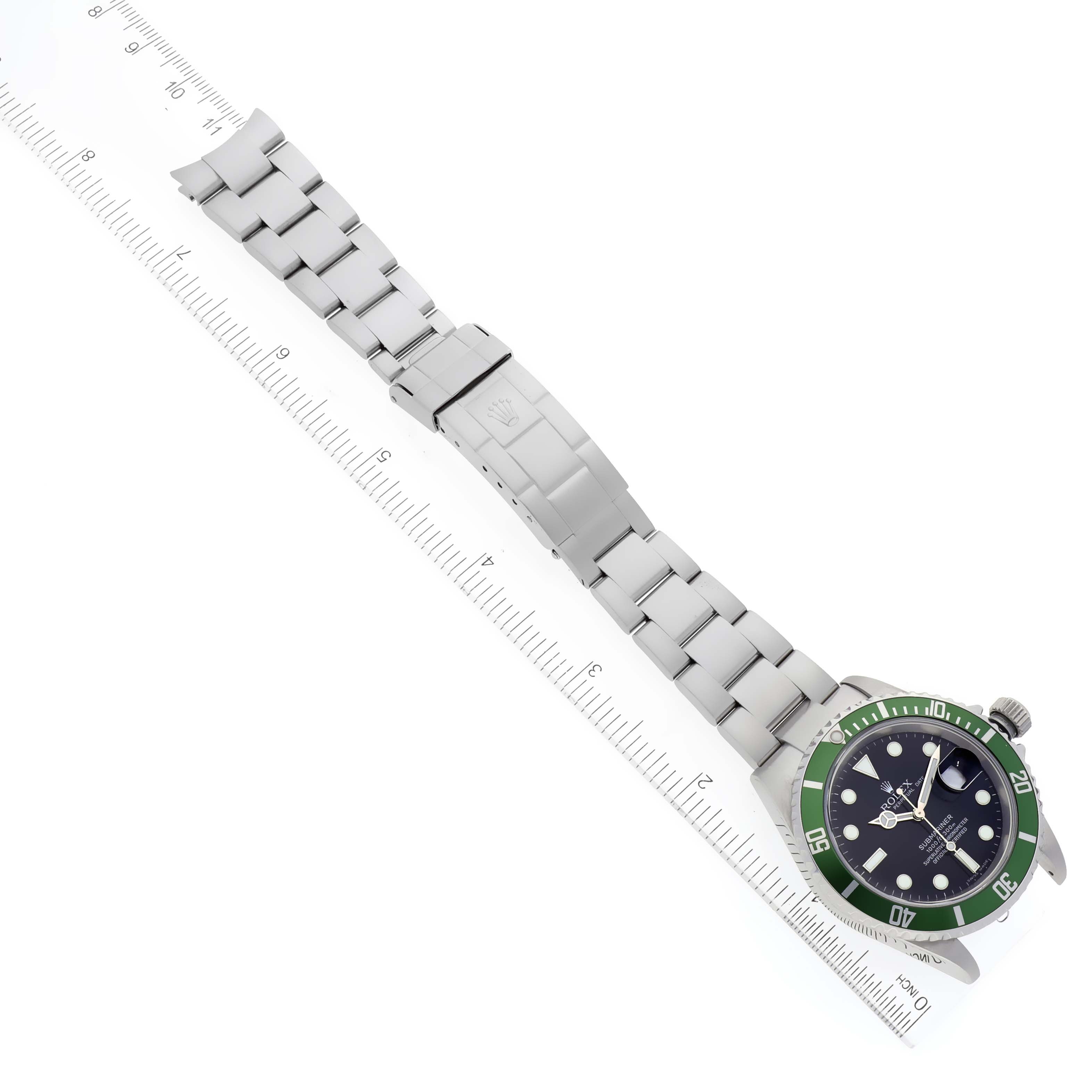 The image shows a side view of a Rolex Submariner 16610LV Men's Stainless Steel Black Dial 16610LV Men's Stainless Steel Black Dial watch, including its band and clasp, placed next to a ruler.