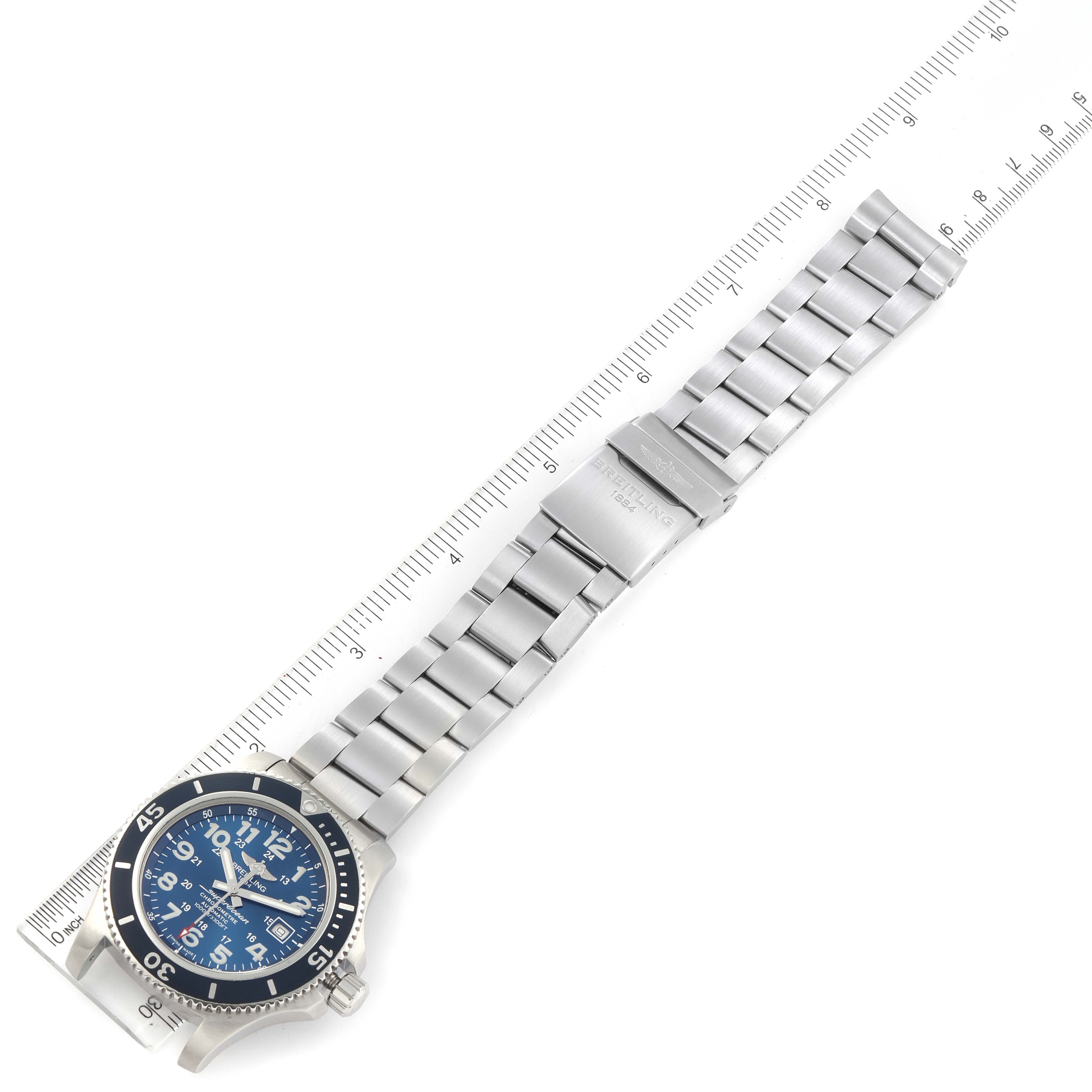 The image shows a top-down view of the Breitling Superocean A17392D8/C910 Men's Stainless Steel Blue Dial A17392D8/C910 Men's Stainless Steel Blue Dial watch, including its blue dial and stainless steel bracelet next to a ruler.