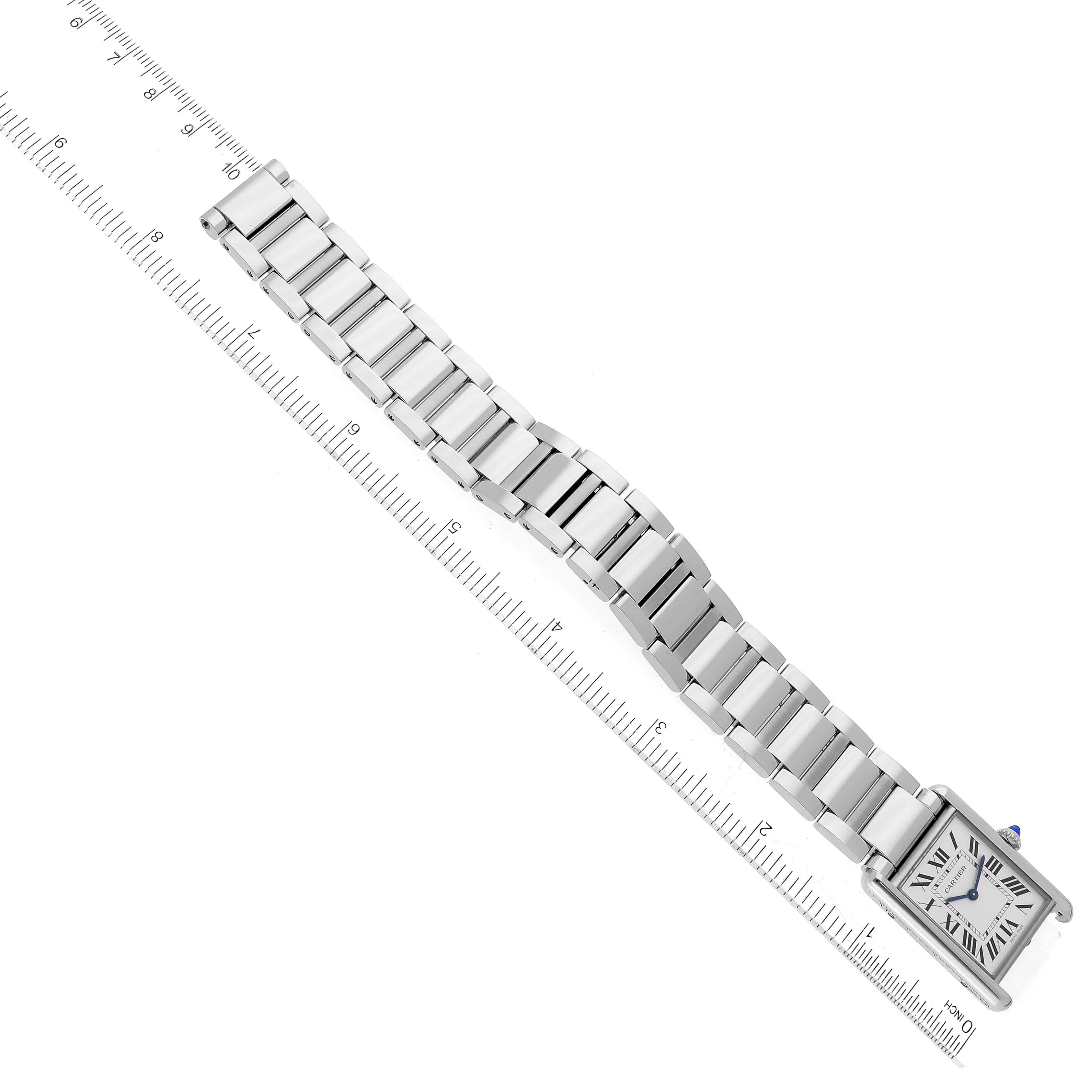 The image shows a top view of a Cartier Tank Must WSTA0052 Women's Stainless Steel Silver Dial WSTA0052 Women's Stainless Steel Silver Dial watch with its metal bracelet extended alongside a ruler.