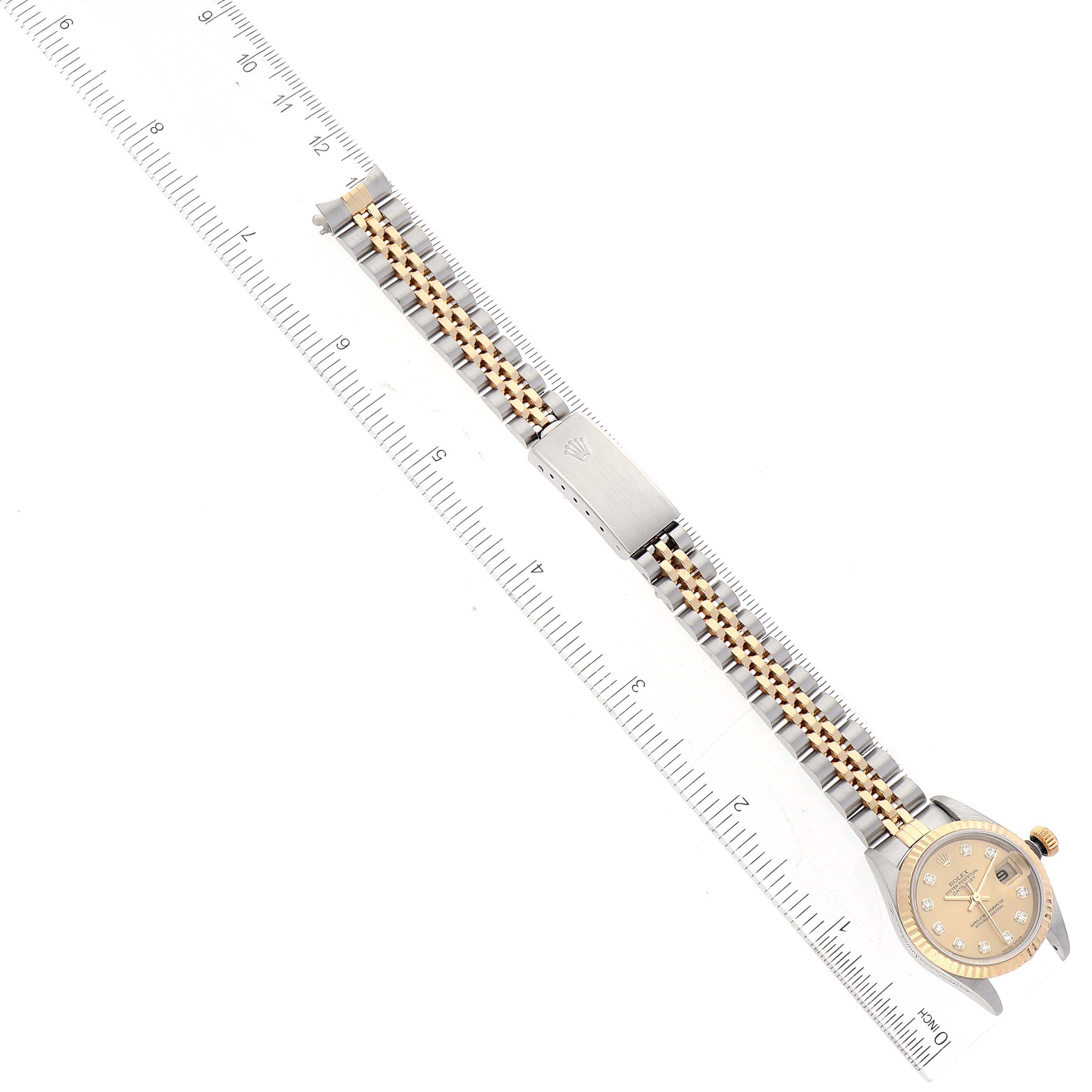 The Rolex Datejust 79173 Women's Steel and Gold (two tone) Champagne Dial 79173 Women's Steel and Gold (two tone) Champagne Dial watch is shown flat from above, fully extended next to a ruler, displaying both the face and the full bracelet.