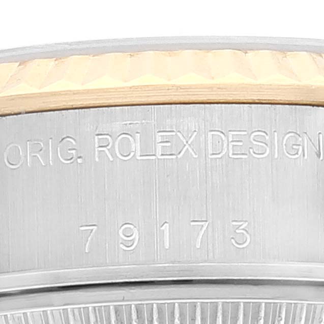 This close-up angle shows the case side of a Rolex Datejust 79173 Women's Steel and Gold (two tone) Champagne Dial 79173 Women's Steel and Gold (two tone) Champagne Dial model, highlighting part of the fluted bezel and engraved text.