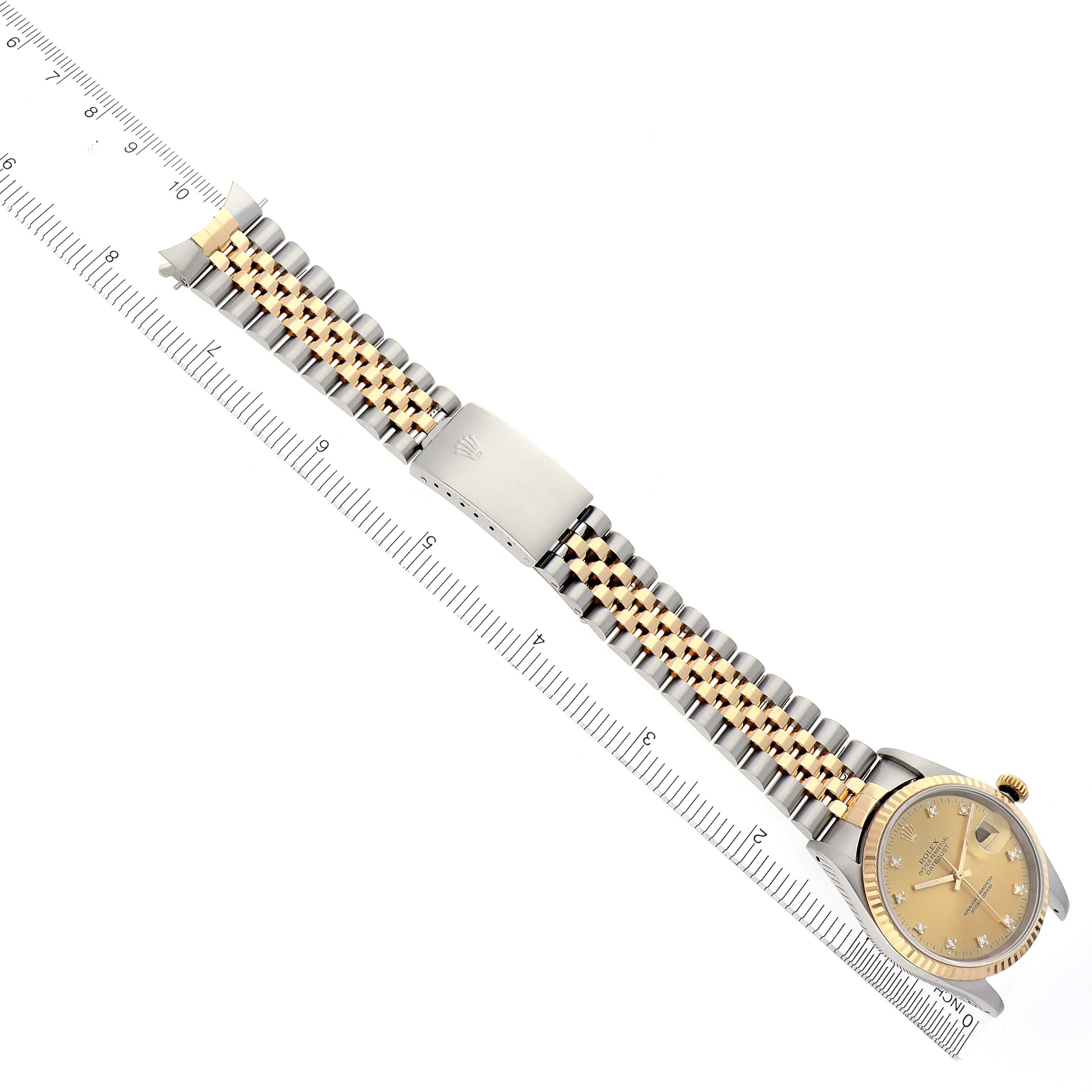 The Rolex Datejust 16233 Men's Steel and Gold (two tone) Champagne Dial 16233 Men's Steel and Gold (two tone) Champagne Dial watch is shown at a diagonal angle, displaying the dial, bracelet, and clasp beside a ruler.