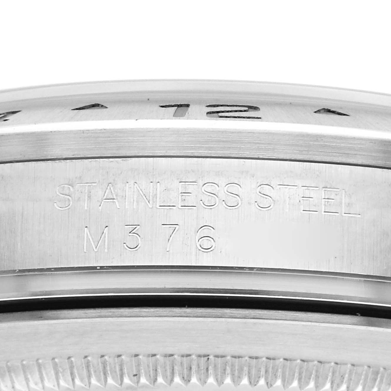 The image shows a close-up of the Rolex Explorer 16570 Men's Stainless Steel White Dial 16570 Men's Stainless Steel White Dial's stainless steel case with engraved text and partial view of the bezel.