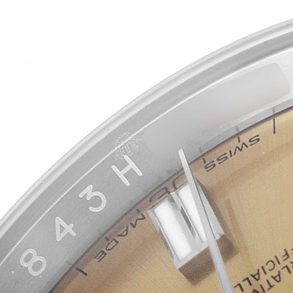 The image shows a close-up angle of the date aperture, hands, and part of the dial and bezel of a Rolex Oyster Perpetual 116000 Men's Stainless Steel Champagne Dial 116000 Men's Stainless Steel Champagne Dial watch.