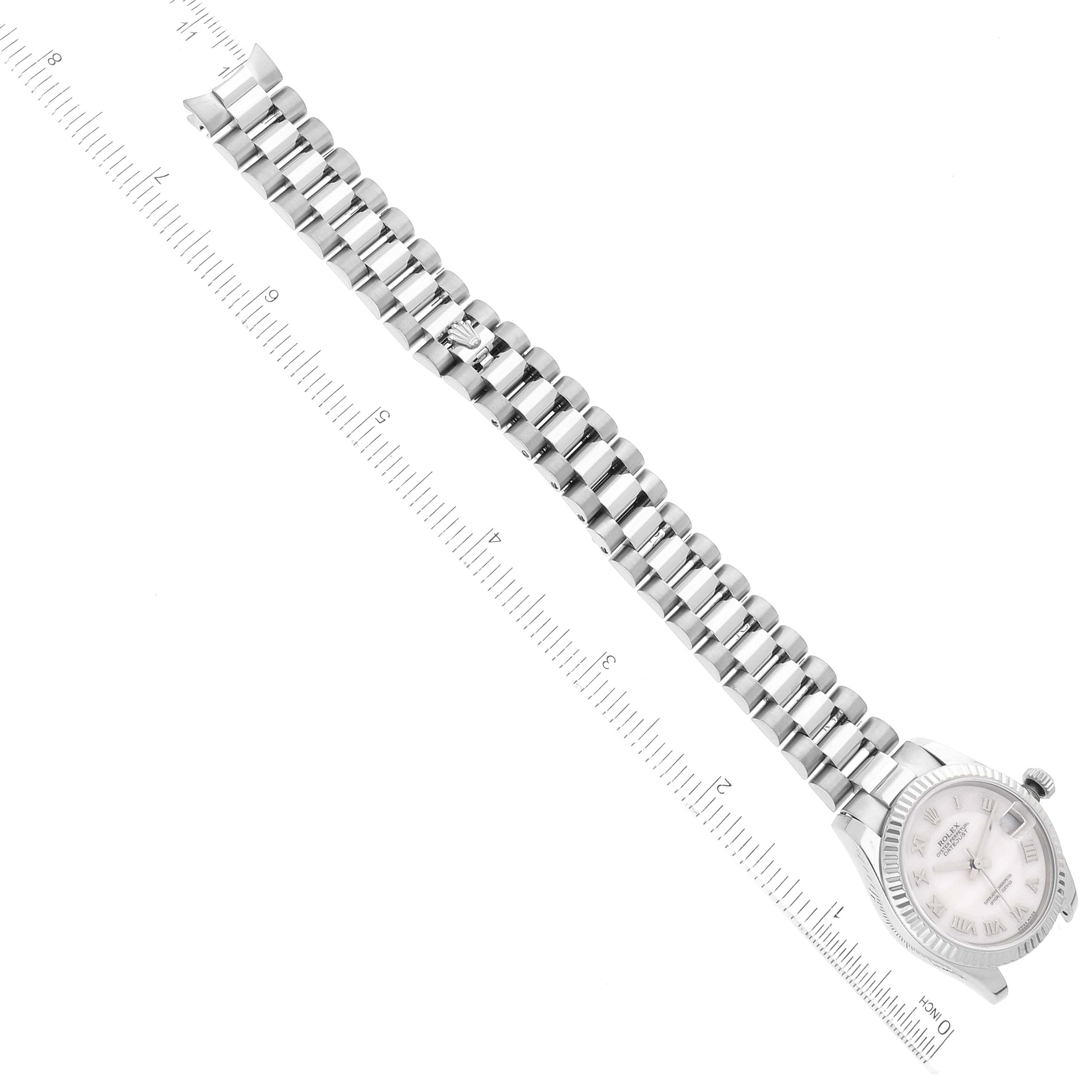 The image shows a top view of a Rolex President 178279 Women's White Gold Mother of Pearl Dial 178279 Women's White Gold Mother of Pearl Dial watch, focusing on the bracelet and dial, accompanied by a measuring ruler.