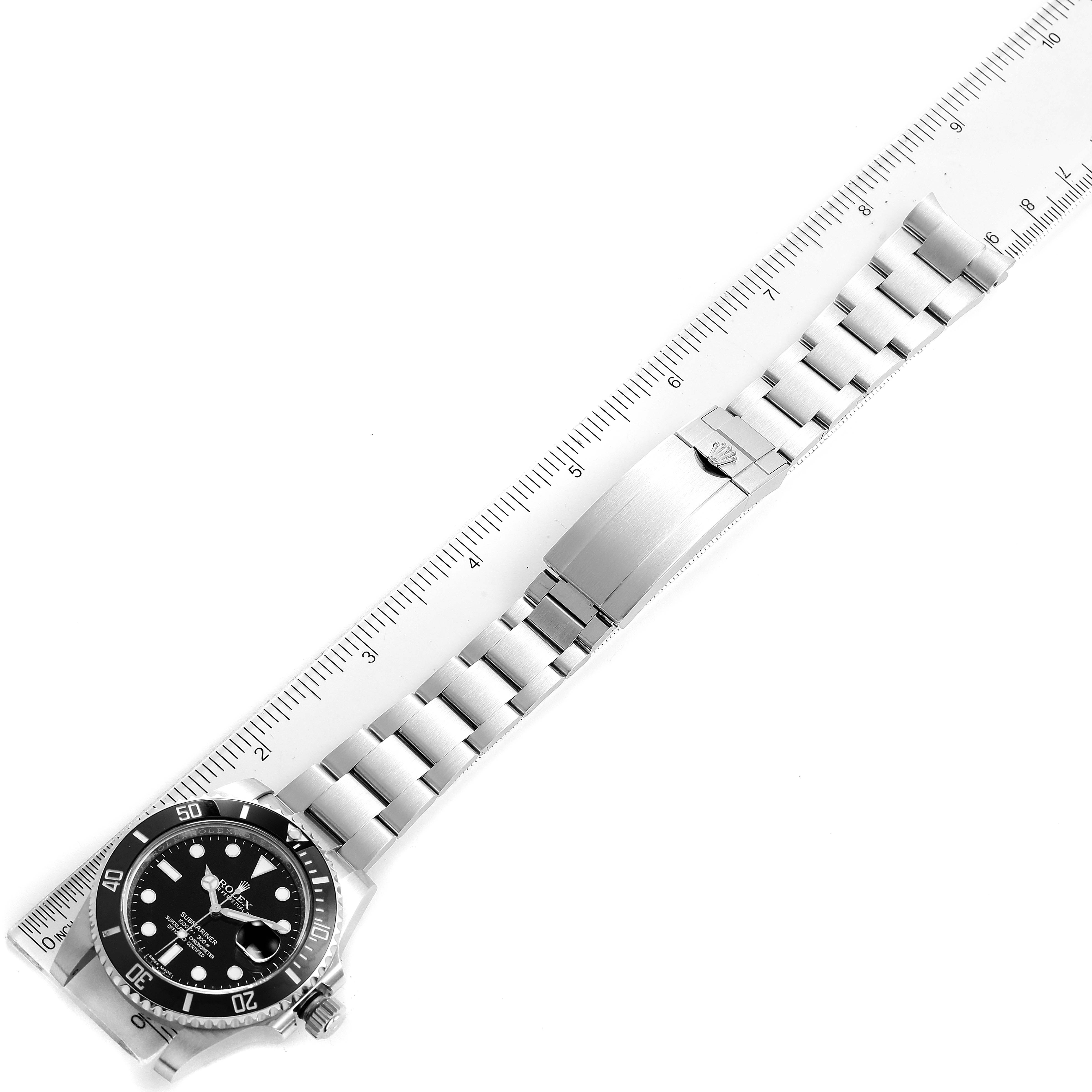 The image shows a top-down view of a Rolex Submariner 116610 Men
s Stainless Steel Black Dial 116610 Men
s Stainless Steel Black Dial watch with its full bracelet laid out next to a ruler.