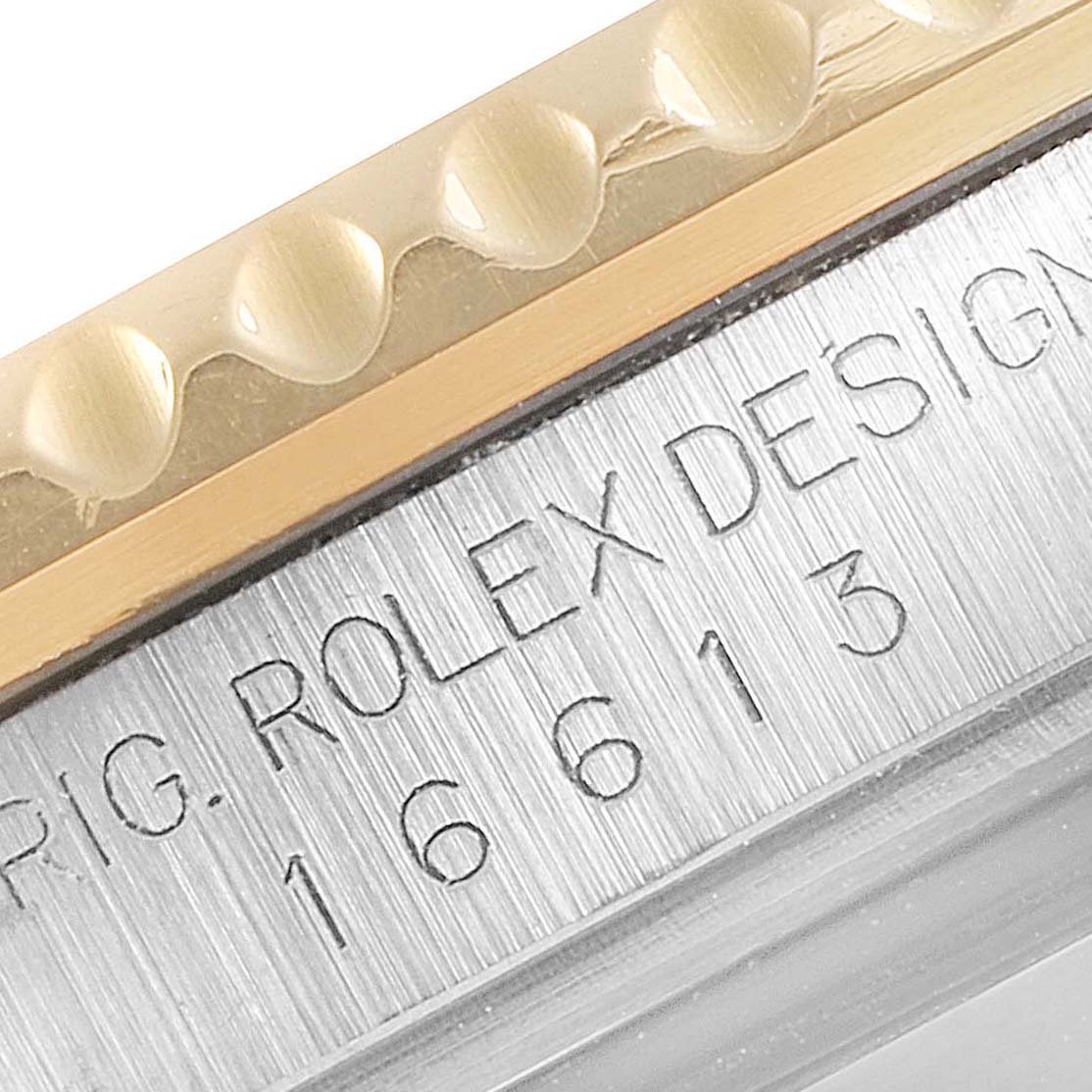 This close-up of a Rolex Submariner 16613 Men's Steel and Gold (two tone) Blue Dial 16613 Men's Steel and Gold (two tone) Blue Dial watch shows part of its bezel and the engraved model number on the case.