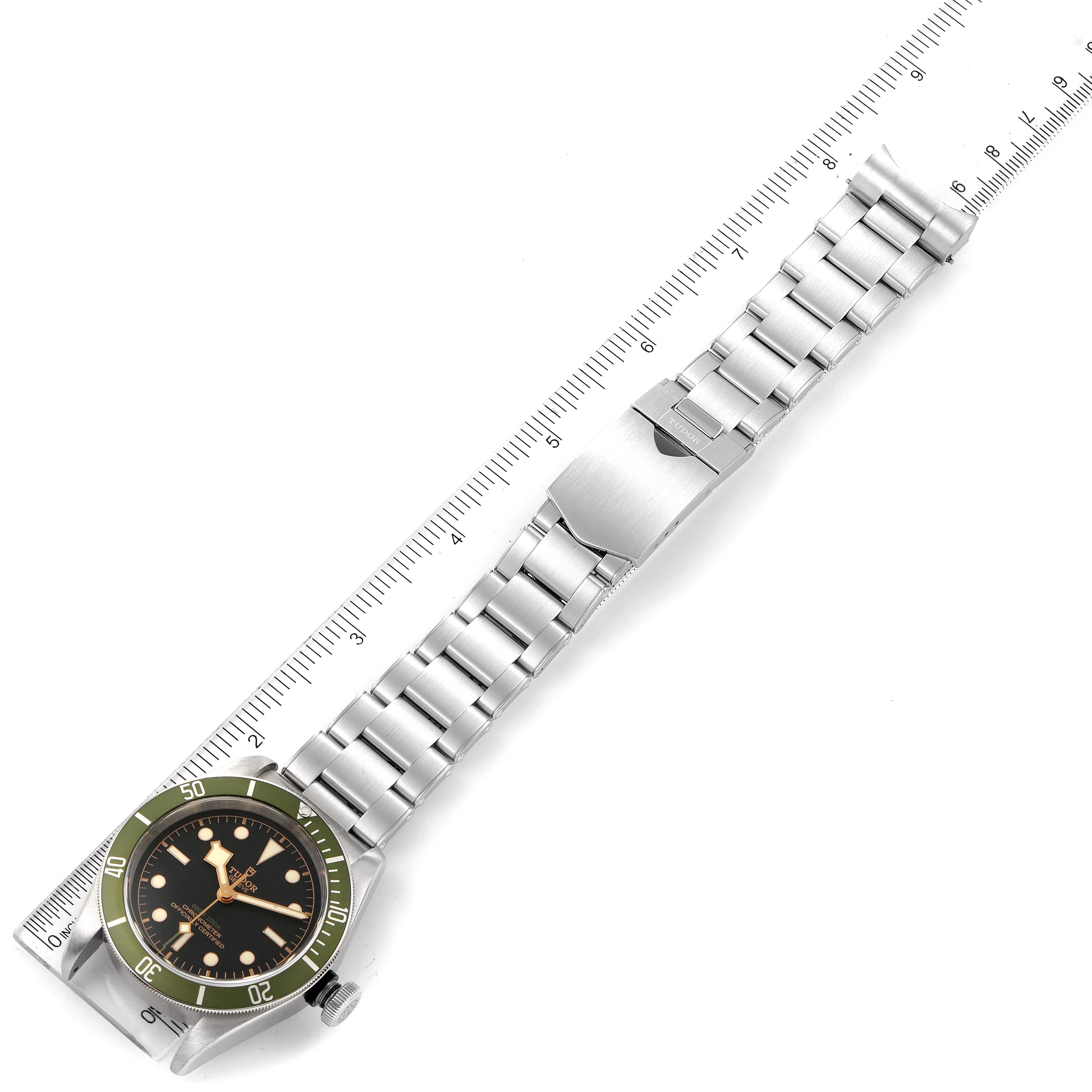 The image shows a Tudor Heritage Black Bay 79230G Men
s Stainless Steel Black Dial 79230G Men
s Stainless Steel Black Dial watch, displayed flat with a stainless steel bracelet and a green bezel.