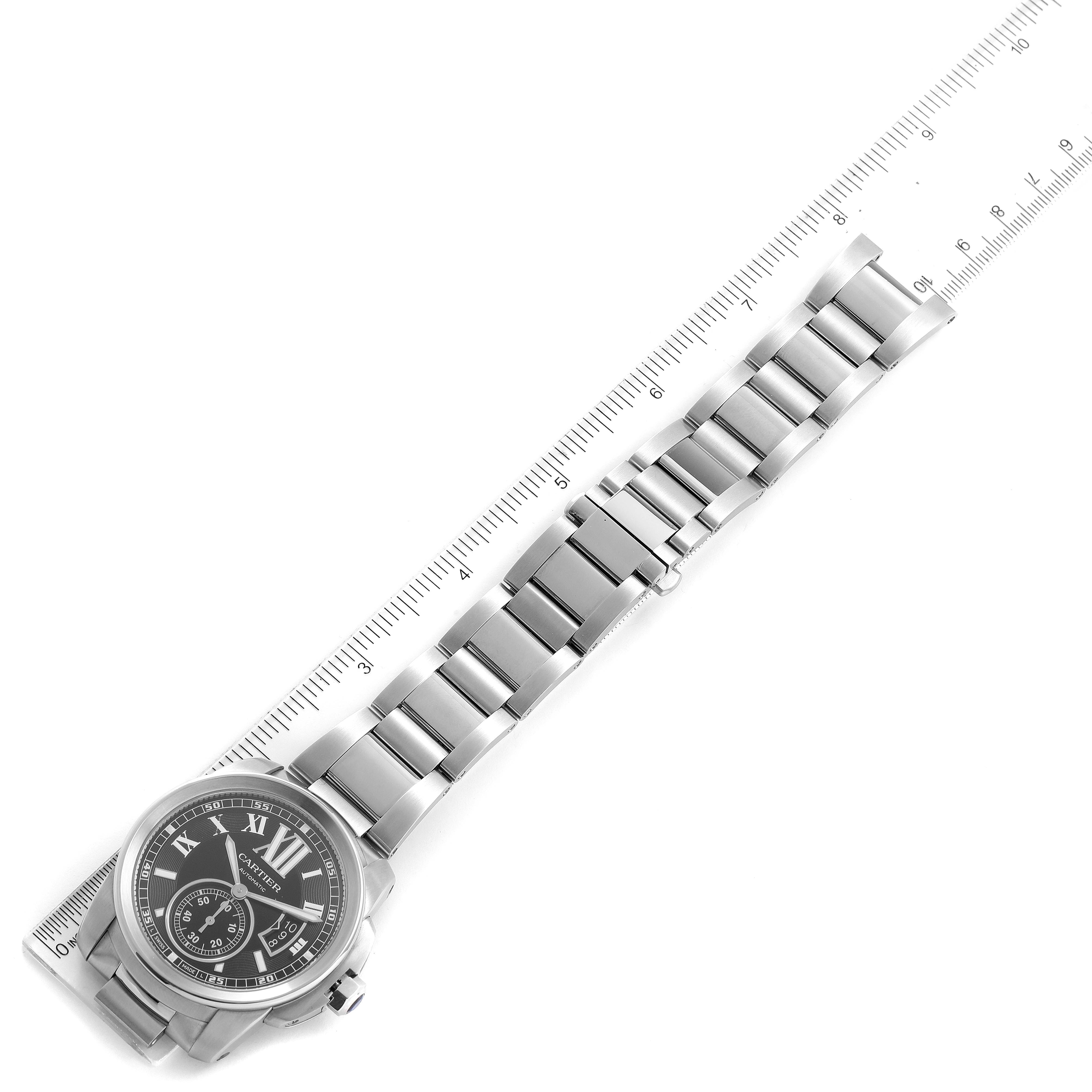 The image shows a top-down view of a Calibre de Cartier watch by Cartier, including the watch face and metal bracelet, alongside a ruler for scale.