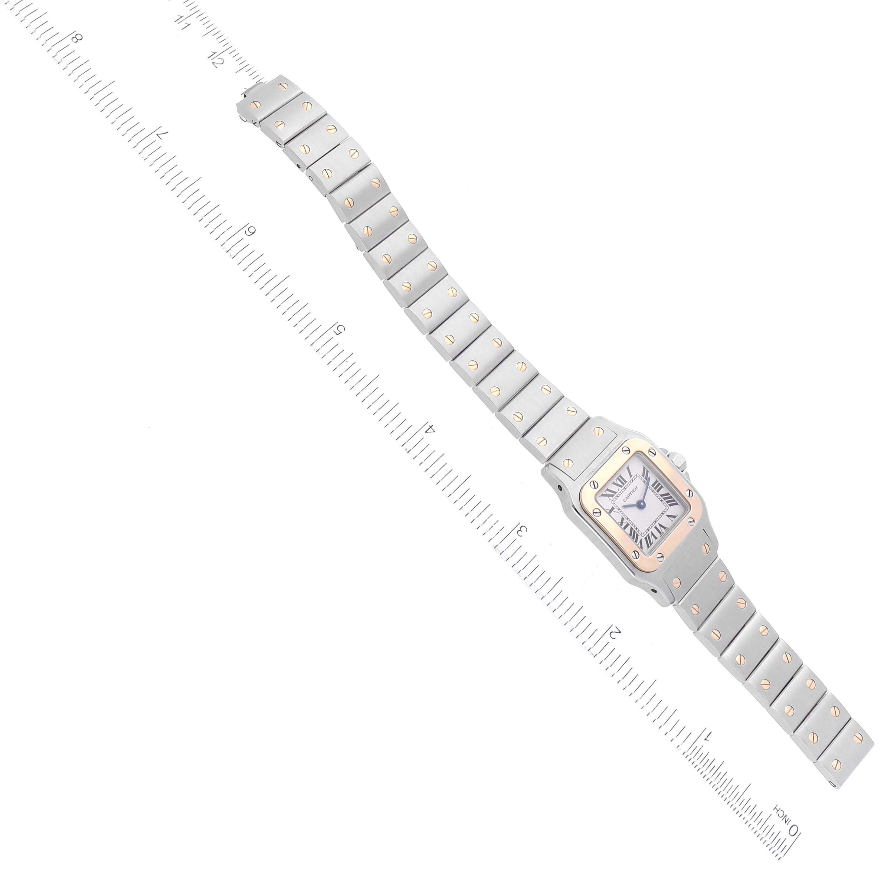 The Cartier Santos W20012C4 Women's Steel and Gold (two tone) Silver Dial W20012C4 Women's Steel and Gold (two tone) Silver Dial watch is shown in a top-down angle, displaying its bracelet, bezel, and dial along with a measuring scale.
