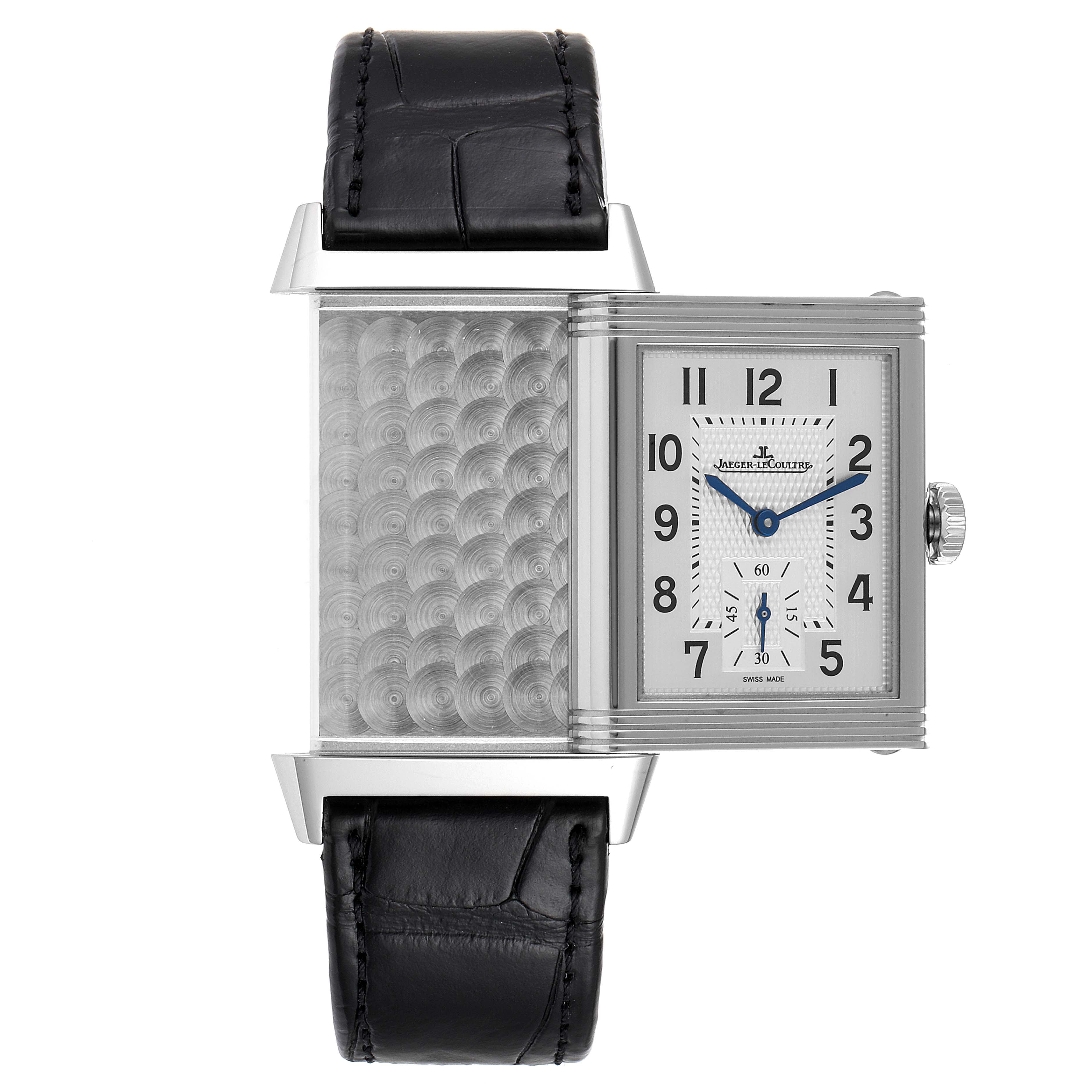 The Jaeger-LeCoultre Reverso watch is shown from the front, with the case rotated to reveal the intricate patterned back.