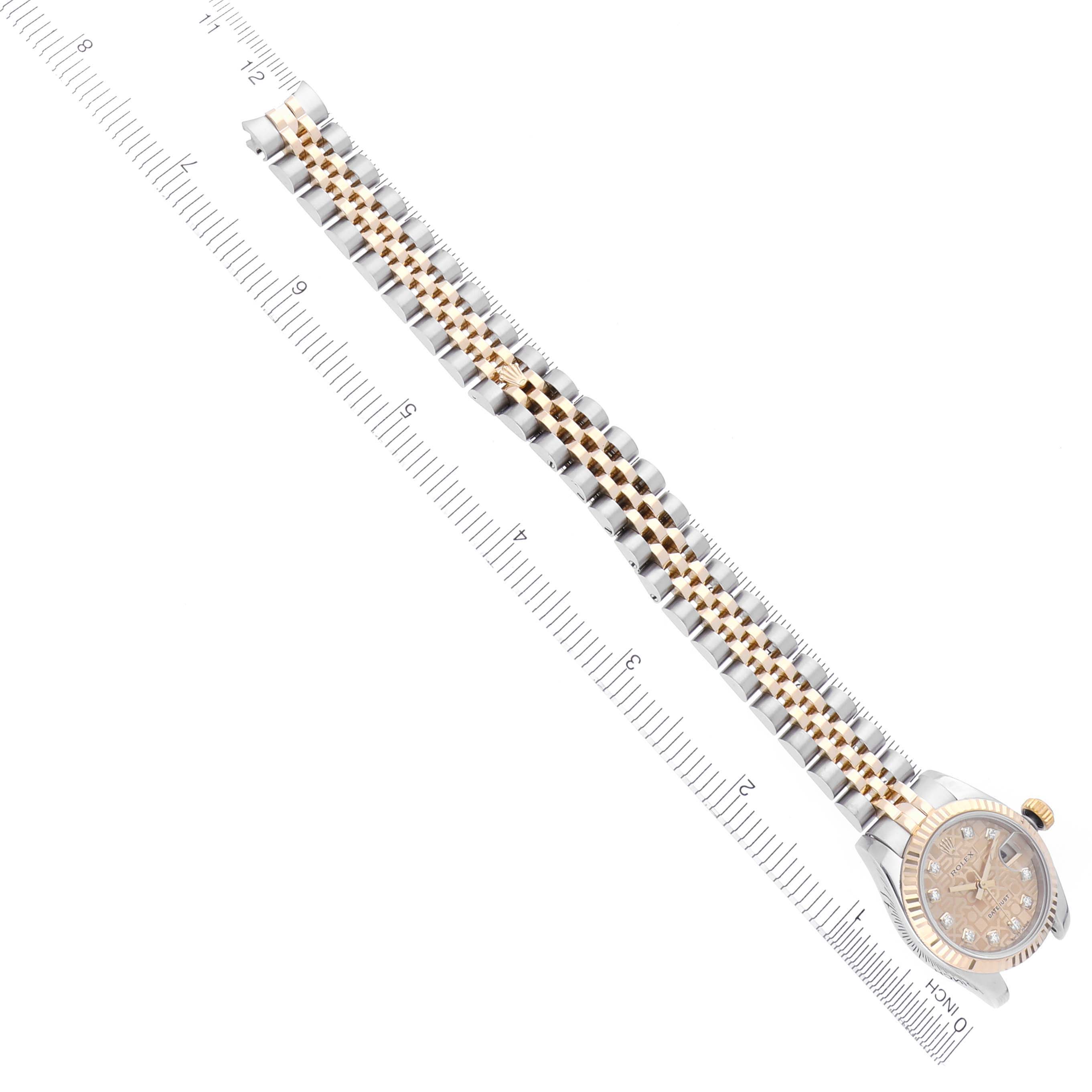 The Rolex Datejust 179173 Women's Steel and Gold (two tone) Champagne Dial 179173 Women's Steel and Gold (two tone) Champagne Dial watch is shown at an angle displaying the bracelet and face with a ruler positioned parallel to it.