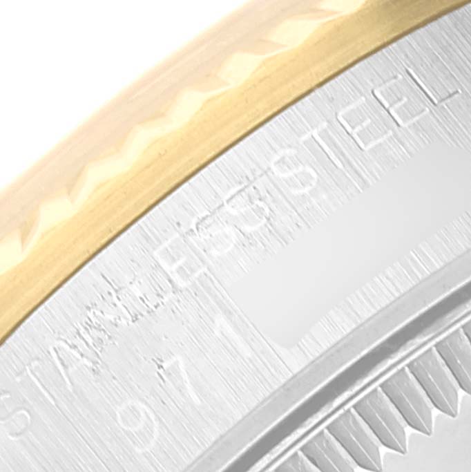 This image shows a close-up of the case edge and part of the bezel of a Mid-Size Rolex watch, highlighting the engraved "Stainless Steel" text.