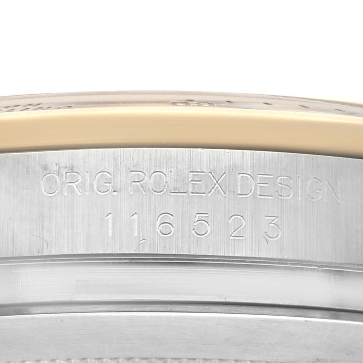 The image shows the side of a Rolex Daytona 116523 Men's Steel and Gold (two tone) Black Dial 116523 Men's Steel and Gold (two tone) Black Dial watch, highlighting the engraved model number and "ORIG. ROLEX DESIGN."