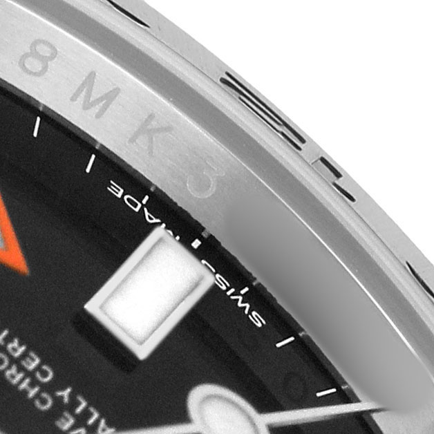 The image shows a close-up of the bezel and dial of a Rolex Explorer 216570 Men's Stainless Steel Black Dial watch, highlighting its markers and part of the text.