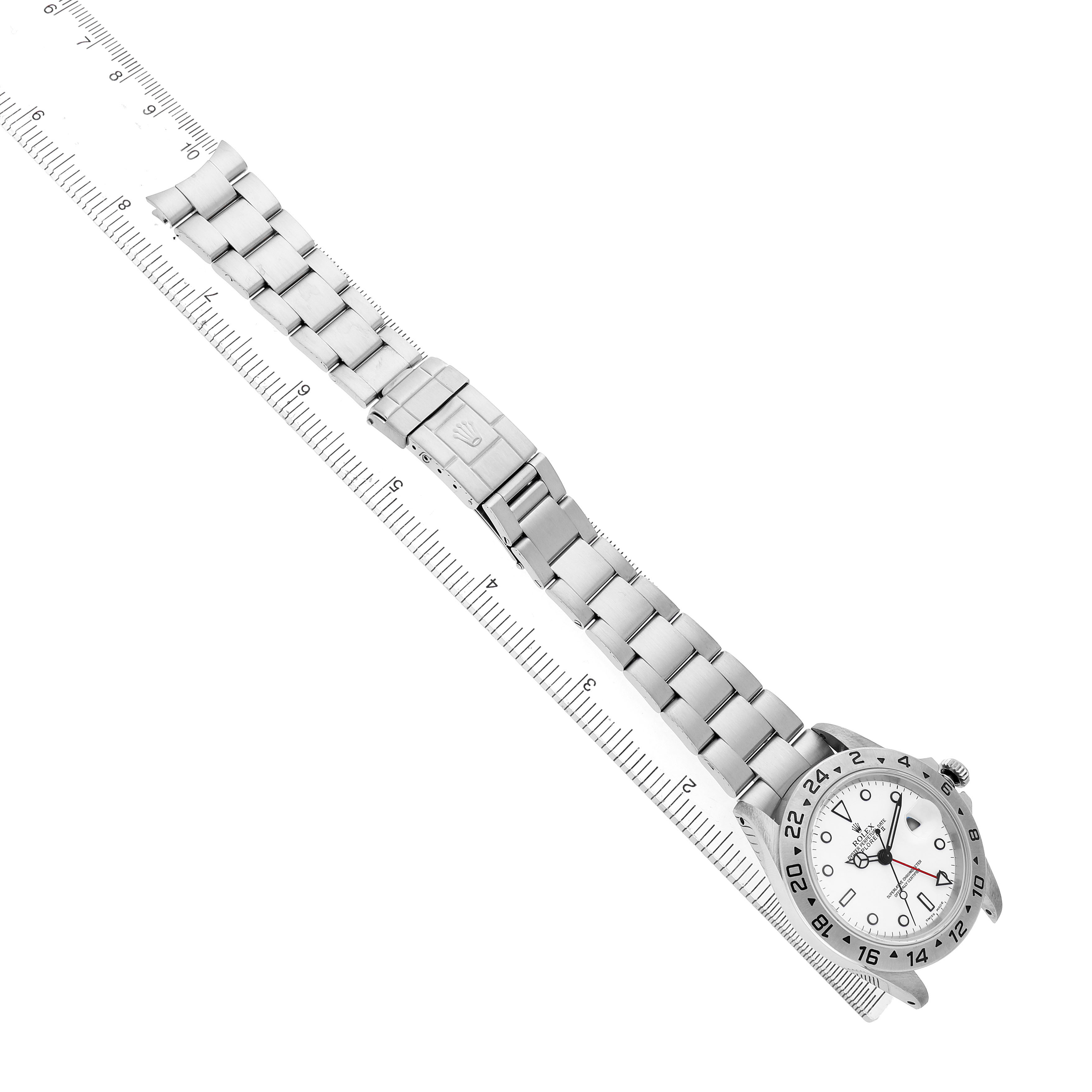 The Rolex Explorer 16570 Men's Stainless Steel White Dial watch is shown from a top-down angle, highlighting its bracelet, clasp, and dial with a ruler beside it.