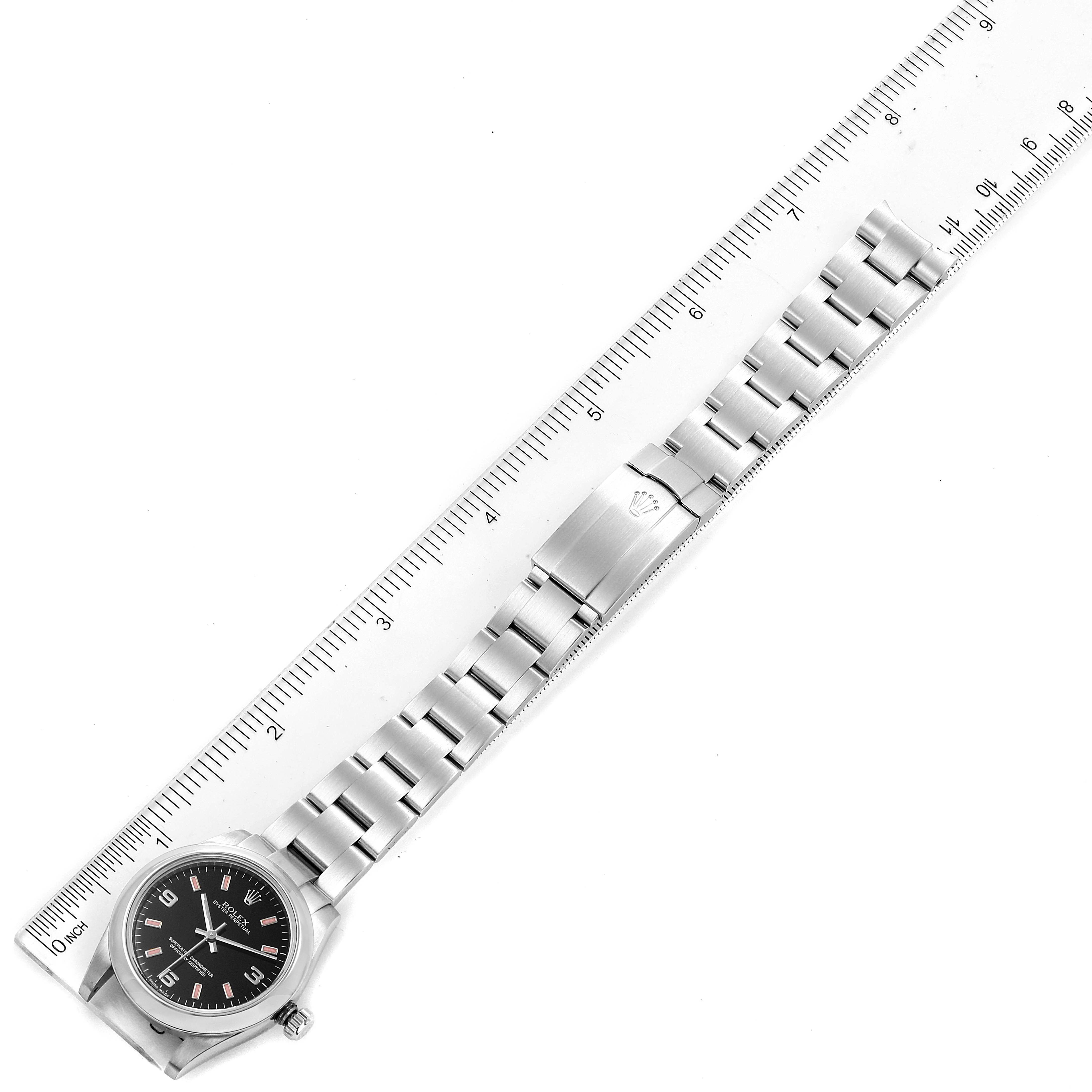 The image shows the full length of a Rolex Mid-Size 177200 Women
s Stainless Steel Black Dial 177200 Women
s Stainless Steel Black Dial model watch laid flat next to a ruler, highlighting the watch face, bracelet, and clasp.