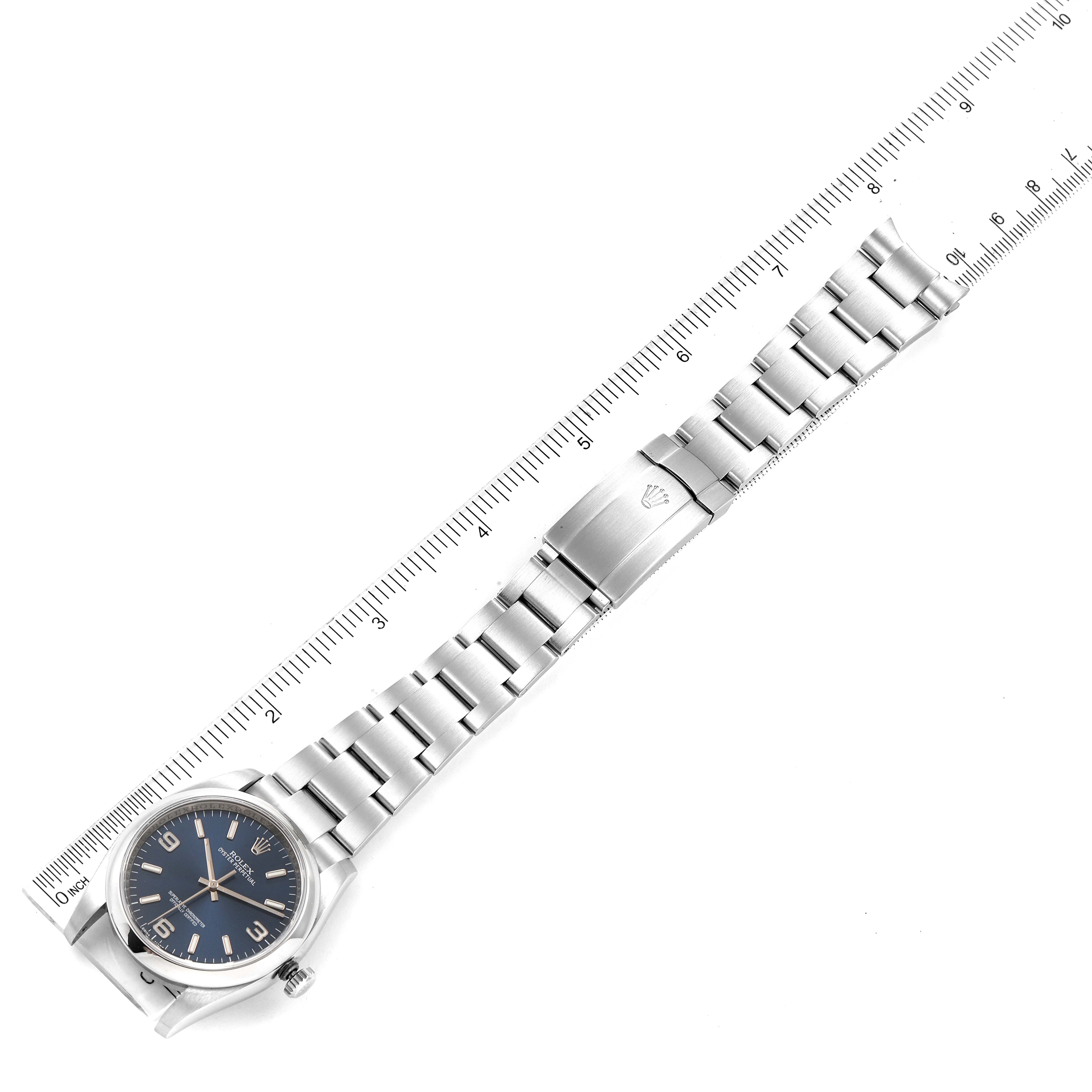 The image shows a top-down view of a Rolex Oyster Perpetual 116000 Men
s Stainless Steel Blue Dial 116000 Men
s Stainless Steel Blue Dial watch with its bracelet and a ruler for scale.
