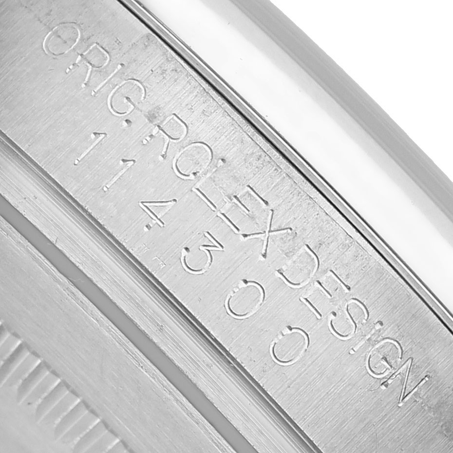 The image shows a close-up of the case engraving on a Rolex Oyster Perpetual 114300 Men's Stainless Steel Silver Dial, displaying "ORIG ROLEX DESIGN 114300."