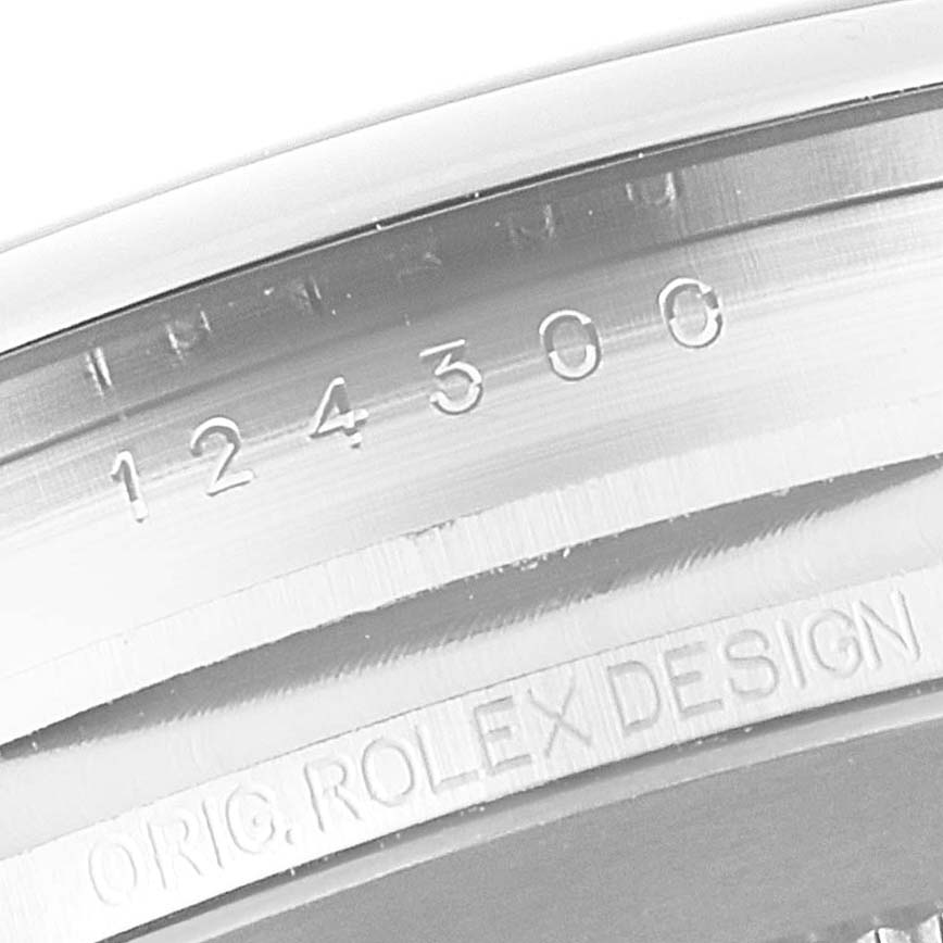 This image shows a close-up angled view of the bezel with etched text on a Rolex Oyster Perpetual 124300 Men's Stainless Steel Silver Dial 124300 Men's Stainless Steel Silver Dial watch.