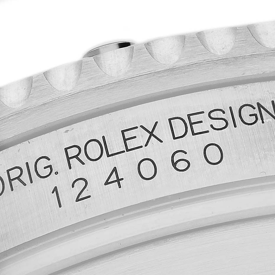 The image shows a close-up of the engraved side of a Rolex Submariner M124060-0001 Men's Stainless Steel Black Dial watch case, showcasing the model number and branding.