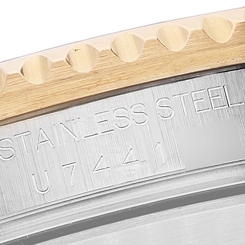 The image shows a close-up view of the bezel and caseback of a Rolex Submariner 16613 Men
s Steel and Gold (two tone) Champagne Dial 16613 Men
s Steel and Gold (two tone) Champagne Dial, revealing the "STAINLESS STEEL" engraving.