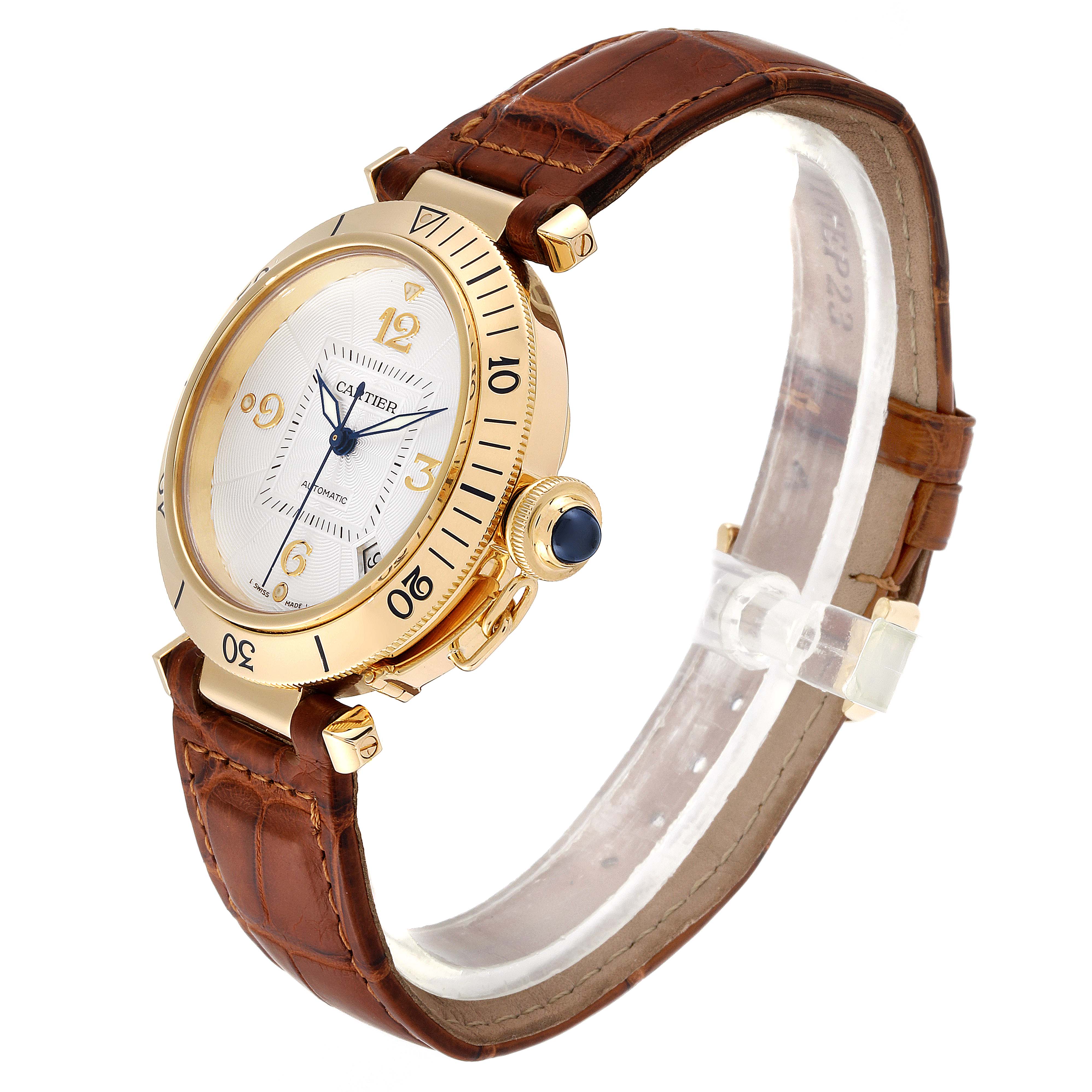 The Cartier Pasha W3004856 Men's Yellow Gold Silver Dial W3004856 Men's Yellow Gold Silver Dial watch is shown from a side angle, displaying its gold case, bezel, dial, and brown leather strap.