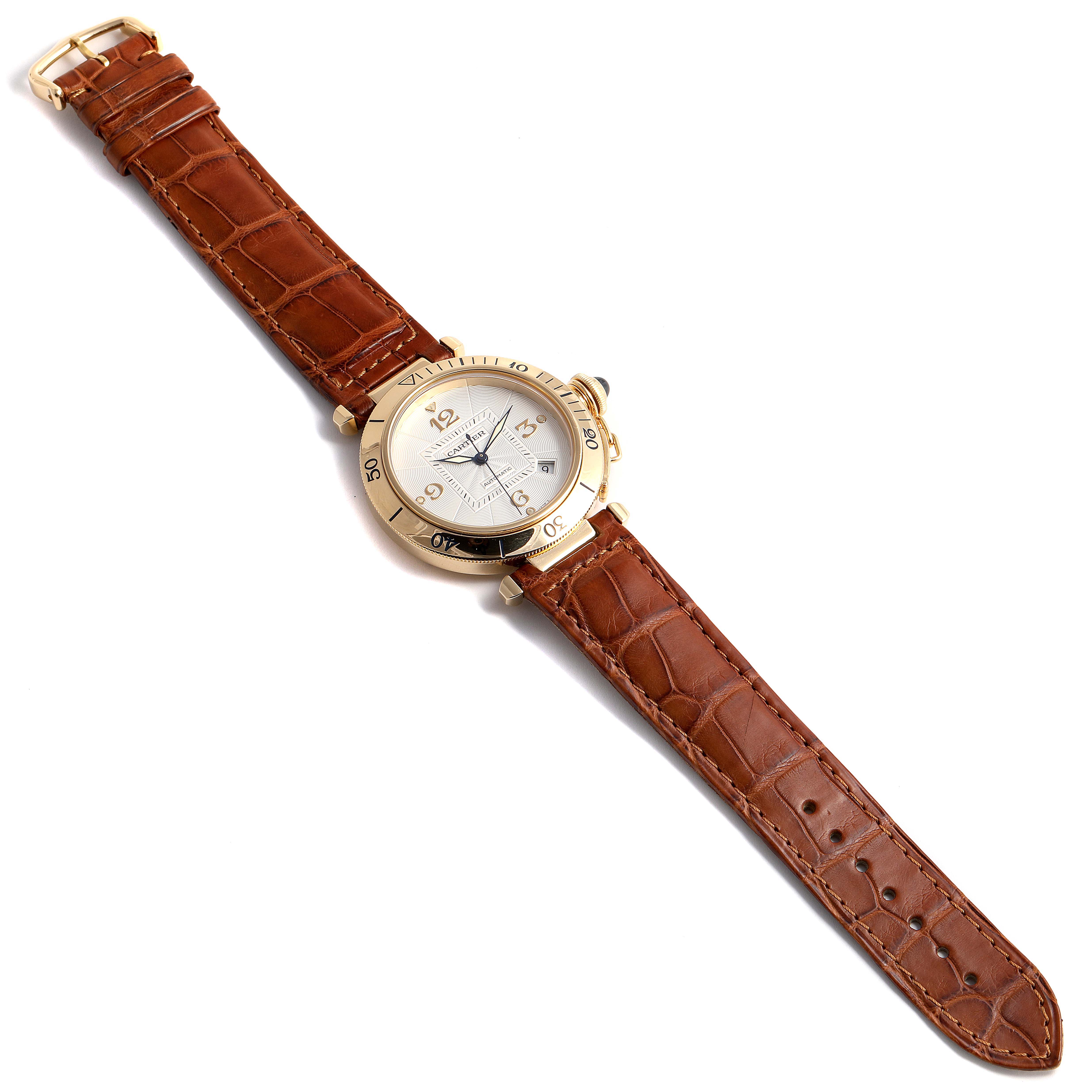 The Cartier Pasha W3004856 Men's Yellow Gold Silver Dial W3004856 Men's Yellow Gold Silver Dial watch is displayed at a top-down angle, showing its face, bezel, and brown leather strap.