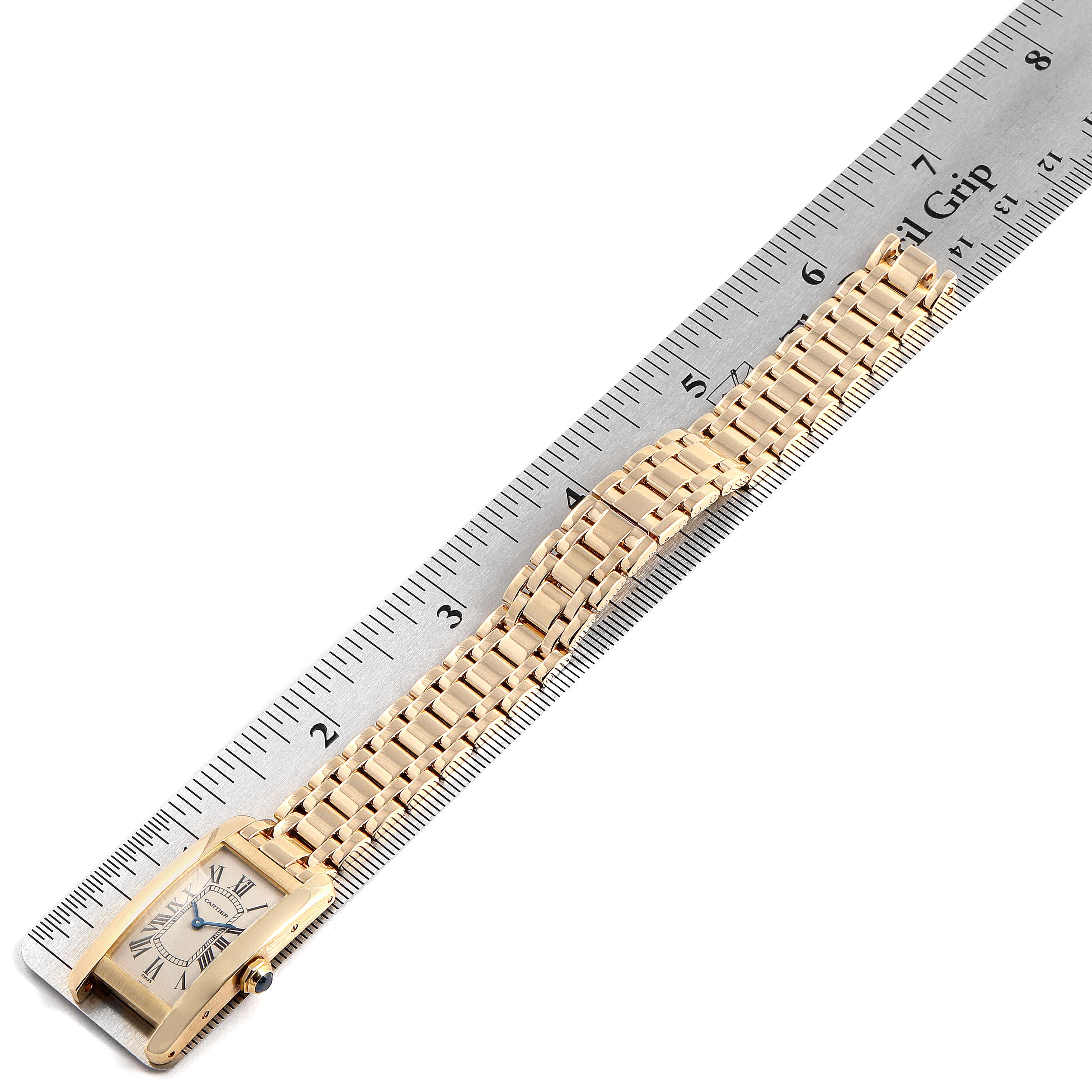 The image shows the Tank Américaine model by Cartier at an overhead angle, displaying the watch face, bracelet, and a ruler for scale.