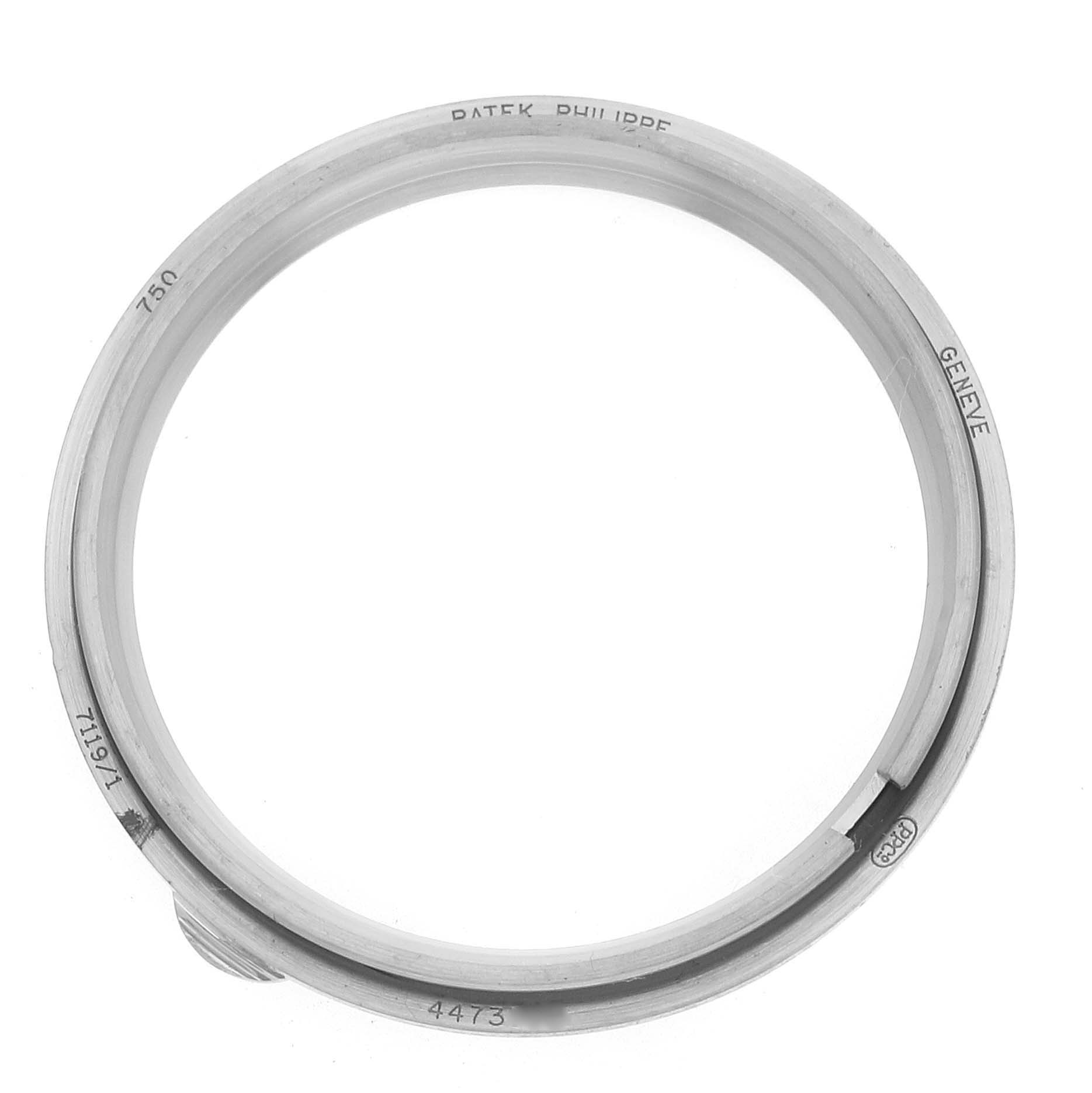 The image shows the bezel of a Patek Philippe Calatrava 7119G Women
s White Gold White Dial watch from a top-down angle, highlighting engraved details.