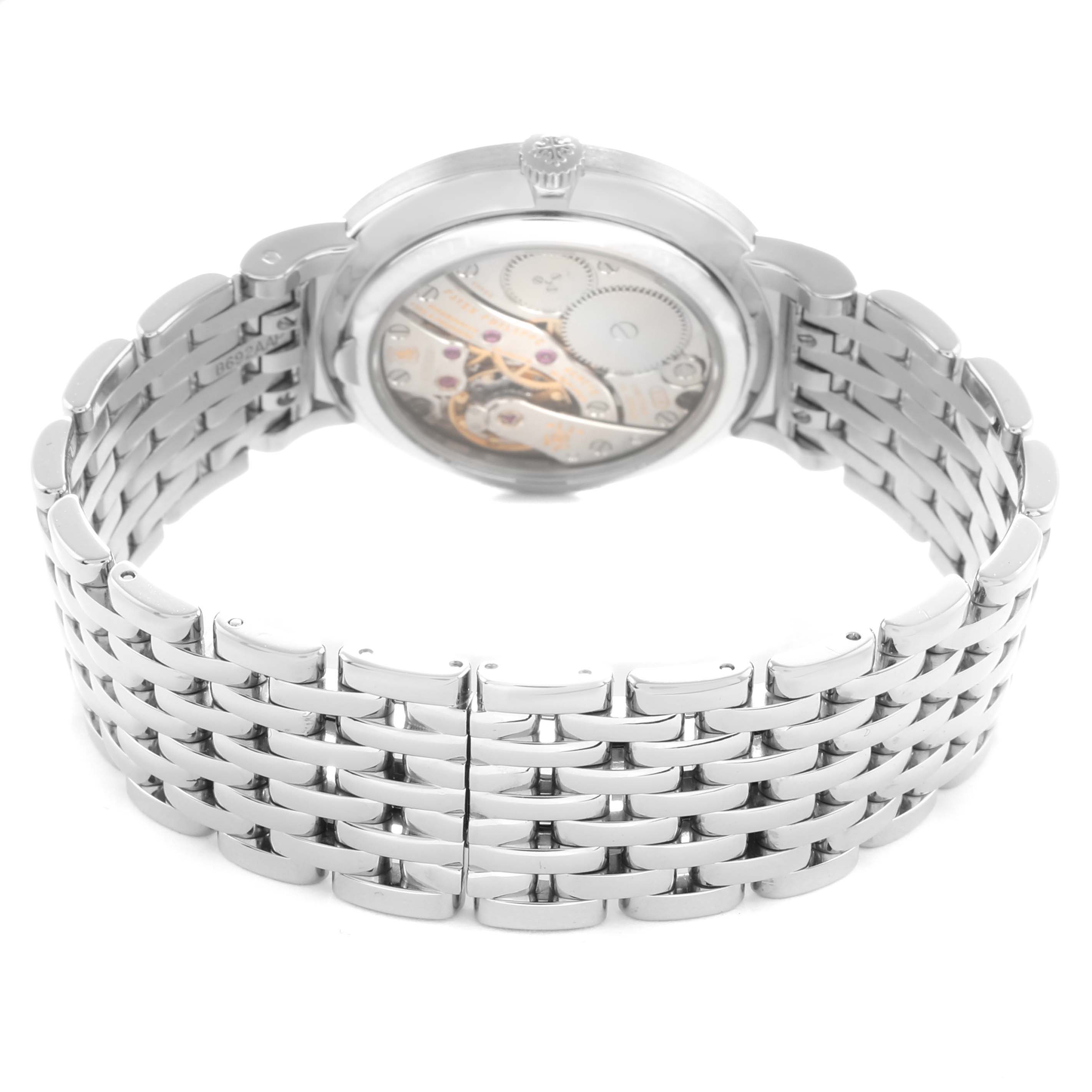 The image shows the back view of a Patek Philippe Calatrava 7119G Women
s White Gold White Dial watch, highlighting its movement and metal bracelet.