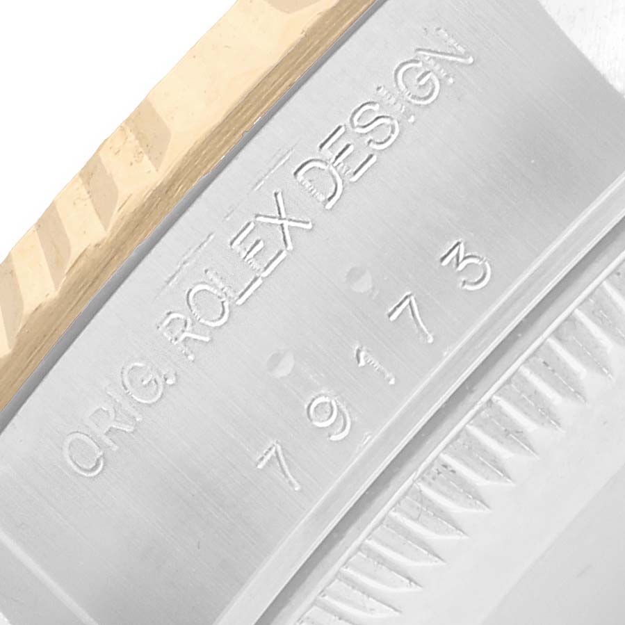 The image shows a close-up of the engraved side of a Rolex Datejust 79173 Women
s Steel and Gold (two tone) Champagne Dial watch case and bezel.