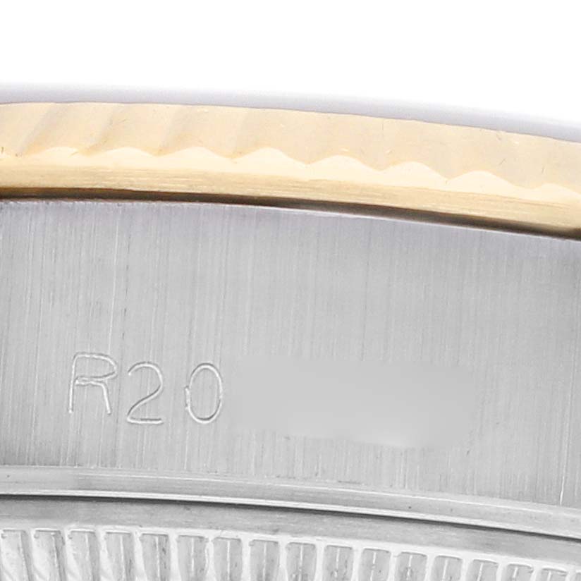 The image shows a close-up of the Rolex Datejust 69173 Women
s Steel and Gold (two tone) Black Dial
s fluted bezel and part of the case, highlighting the engraved detail.