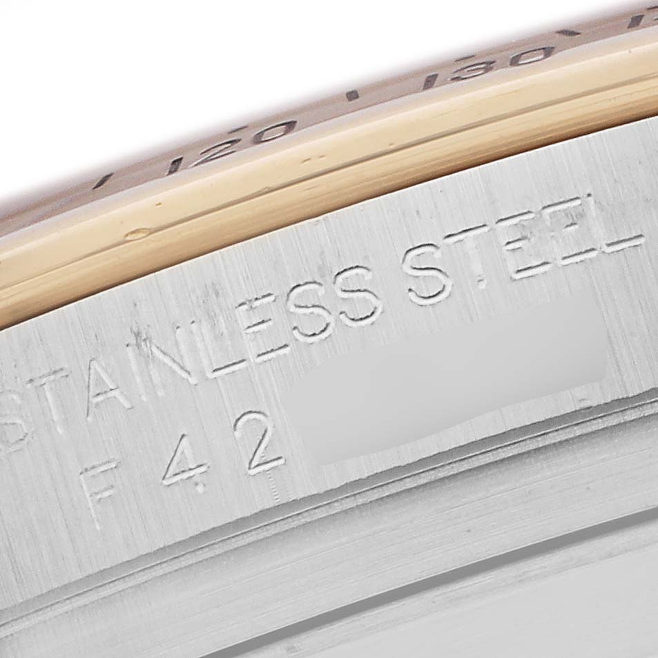 The image shows a close-up of the side of a Rolex Daytona 116523 Men
s Steel and Gold (two tone) Mother of Pearl Dial watch with engravings on the stainless steel surface.