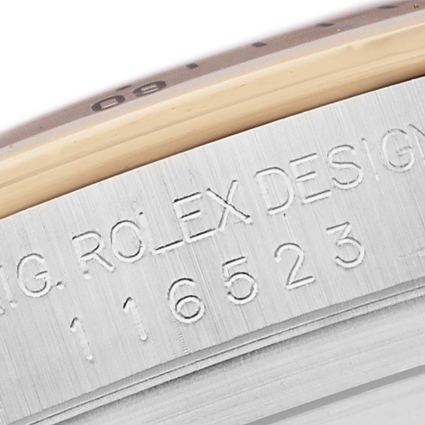 The image shows a close-up angle of the Rolex Daytona 116523 Men
s Steel and Gold (two tone) Mother of Pearl Dial
s edge, highlighting the engraved model number and "ROLEX DESIGN" text.