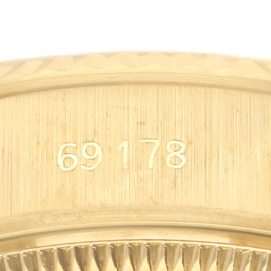 The image shows a close-up of the side of a Rolex President 69178 Women's Yellow Gold Champagne Dial 69178 Women's Yellow Gold Champagne Dial model, focusing on the case edge with engraved details.