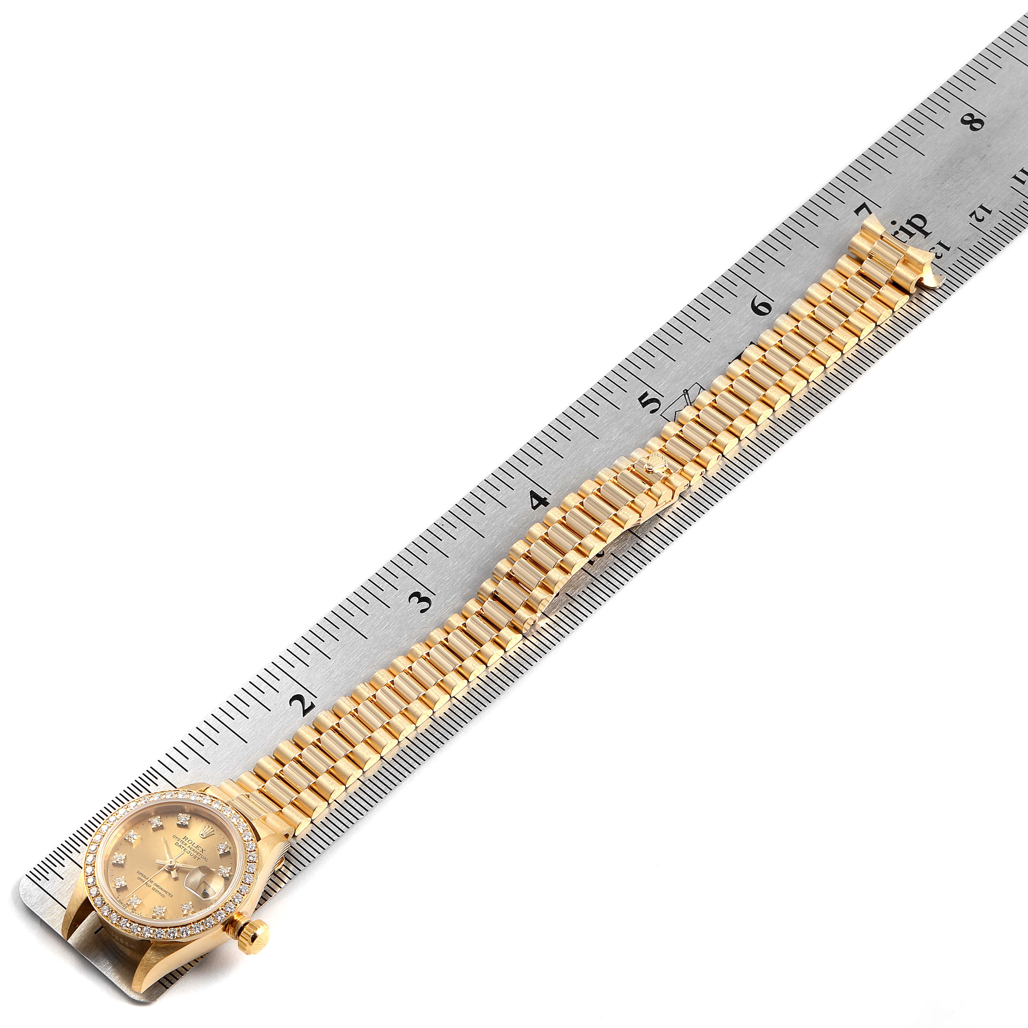 The image shows a Rolex President 69138 Women
s Yellow Gold Champagne Dial 69138 Women
s Yellow Gold Champagne Dial watch fully extended, with the watch head and bracelet placed along a ruler.