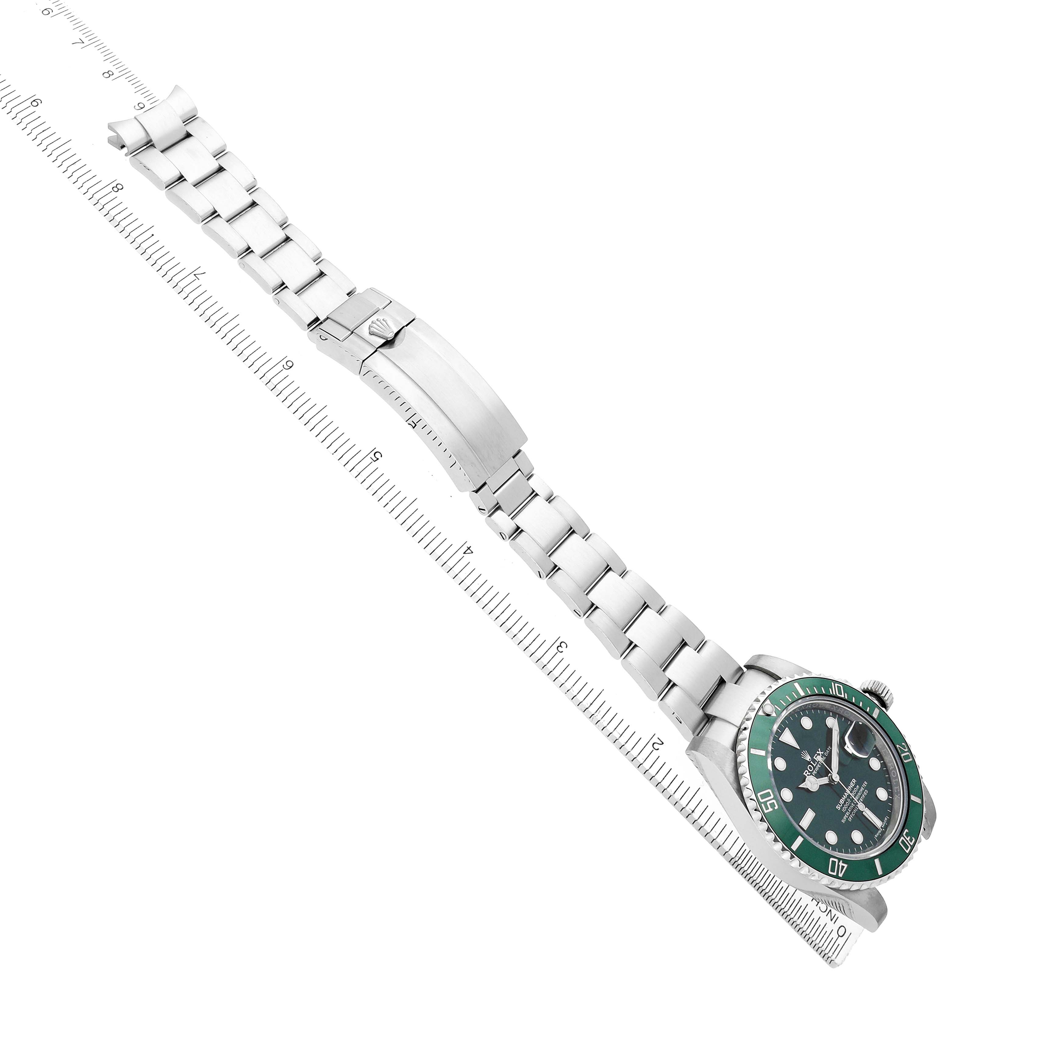 The Rolex Submariner 116610LV Men
s Stainless Steel Green Dial is shown at an angled view, displaying the watch face, bezel, bracelet, and clasp alongside a ruler for scale.