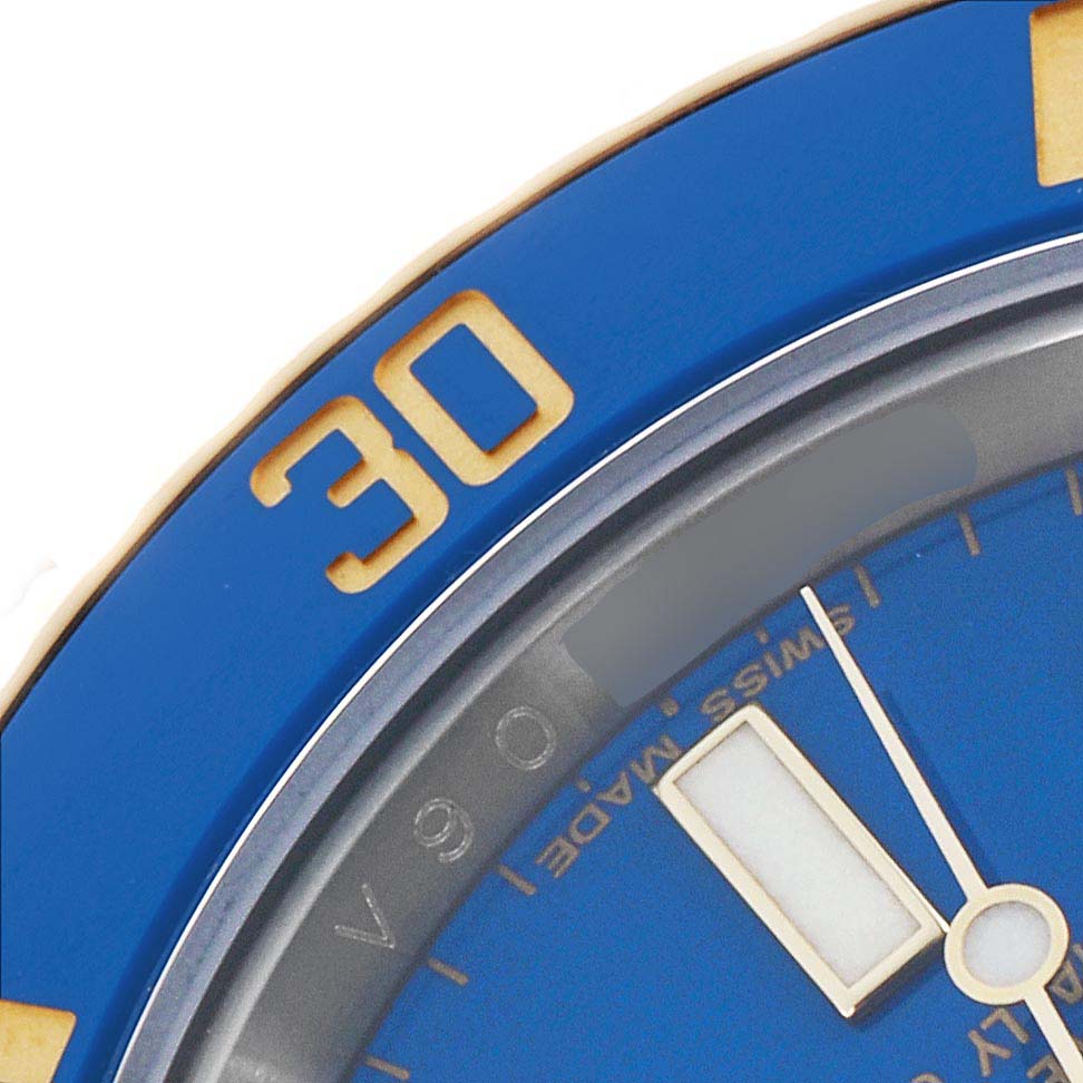 The image shows the bezel and part of the dial of a Rolex Submariner 116613 Men
s Steel and Gold (two tone) Blue Dial, featuring a blue color with gold markings.