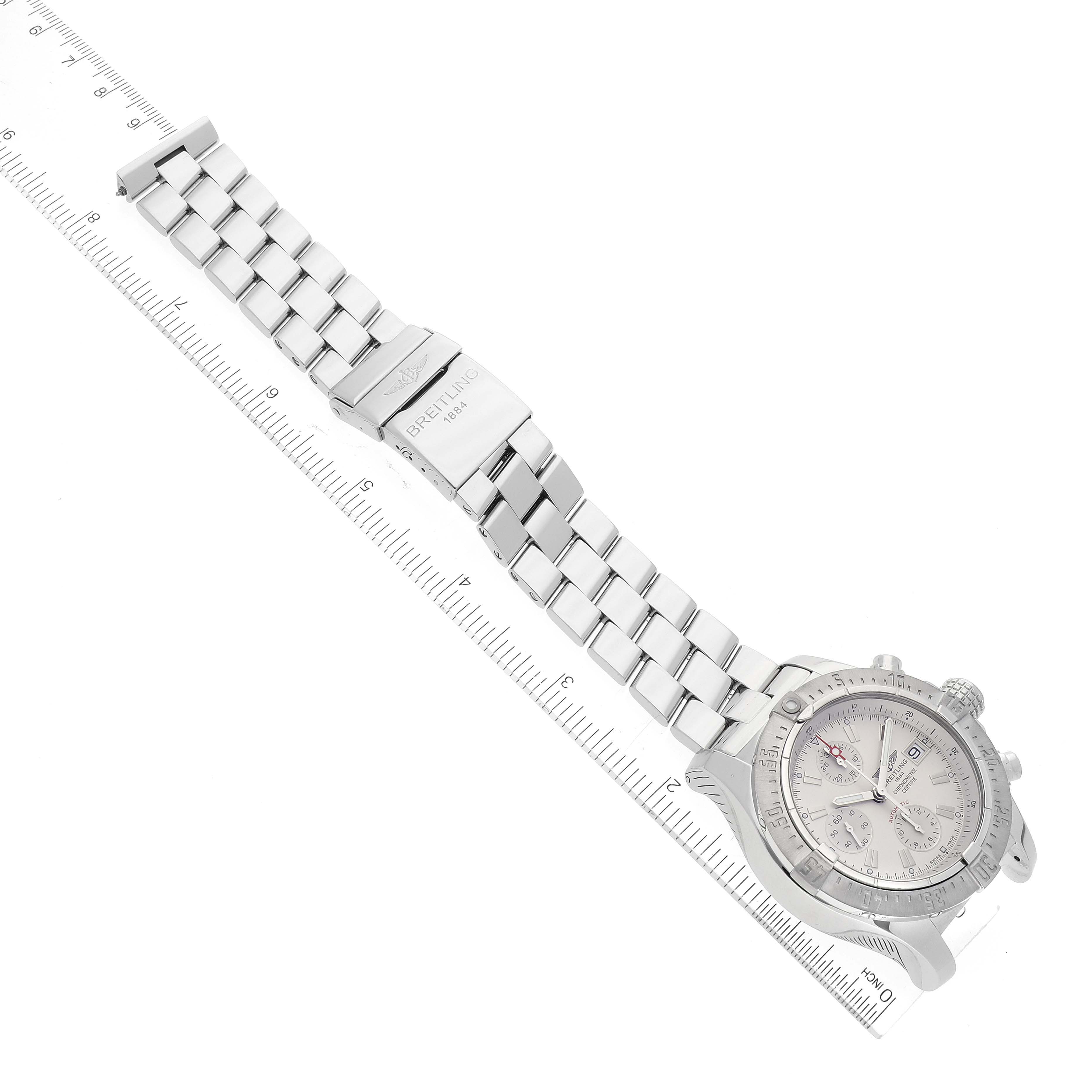 The Breitling Avenger A13380 Men's Stainless Steel Silver Dial A13380 Men's Stainless Steel Silver Dial watch is shown flat with its face, bezel, crown, and metal bracelet fully visible, placed alongside a ruler.