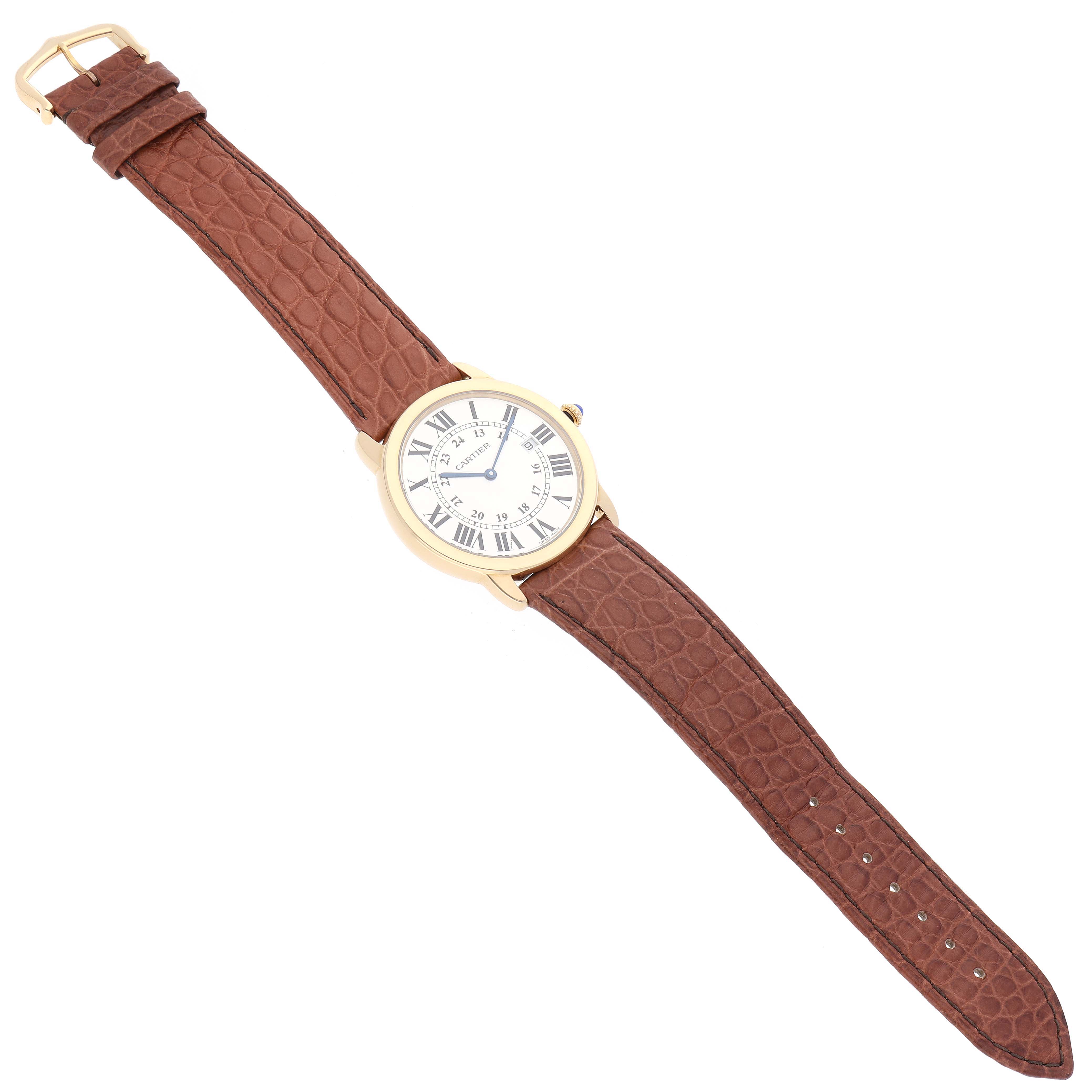 The Ronde model by Cartier is shown from a top-down angle, featuring its watch face, brown leather strap, and gold case.