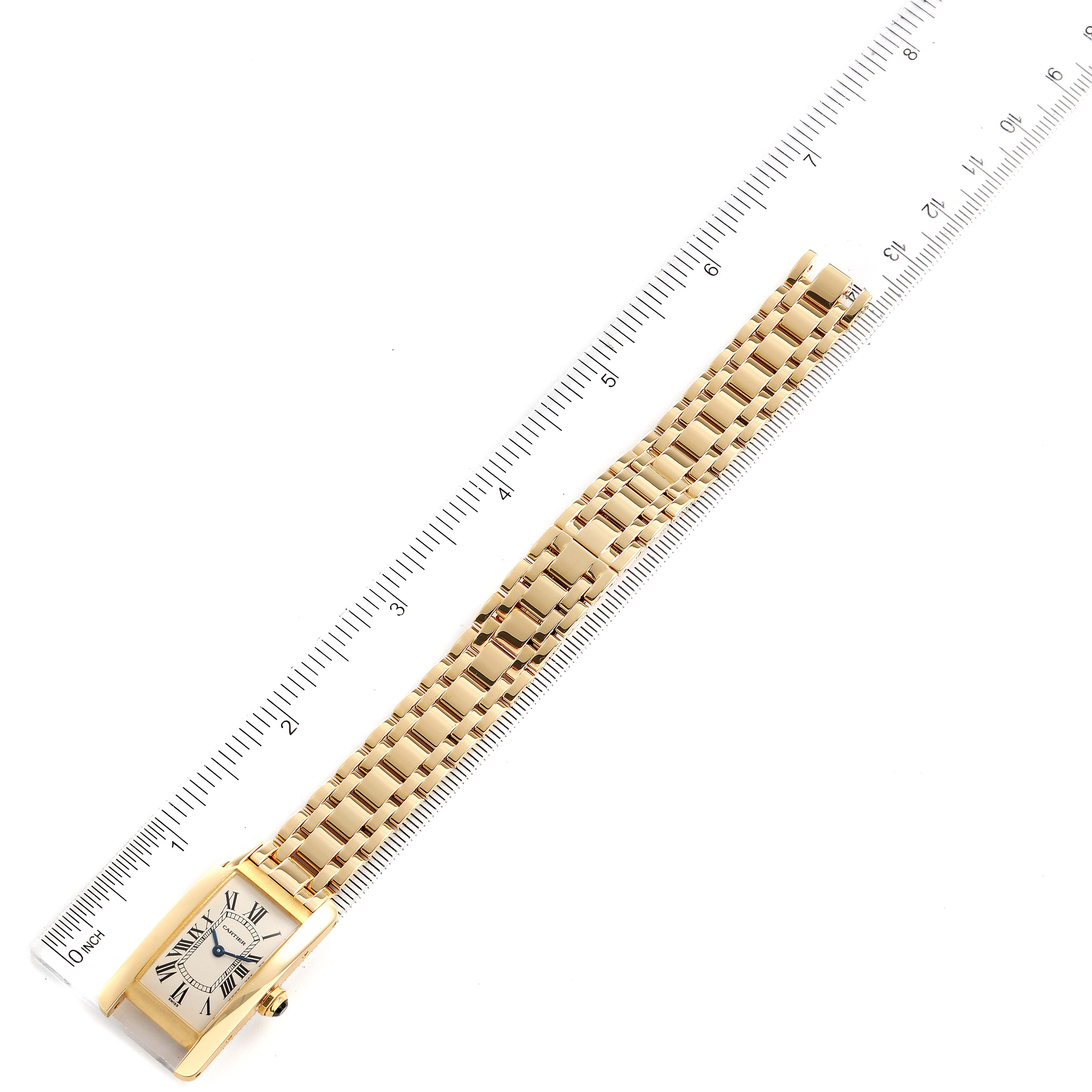 The Tank Americaine watch by Cartier is shown laid flat with its gold bracelet extended, alongside a ruler for scale.