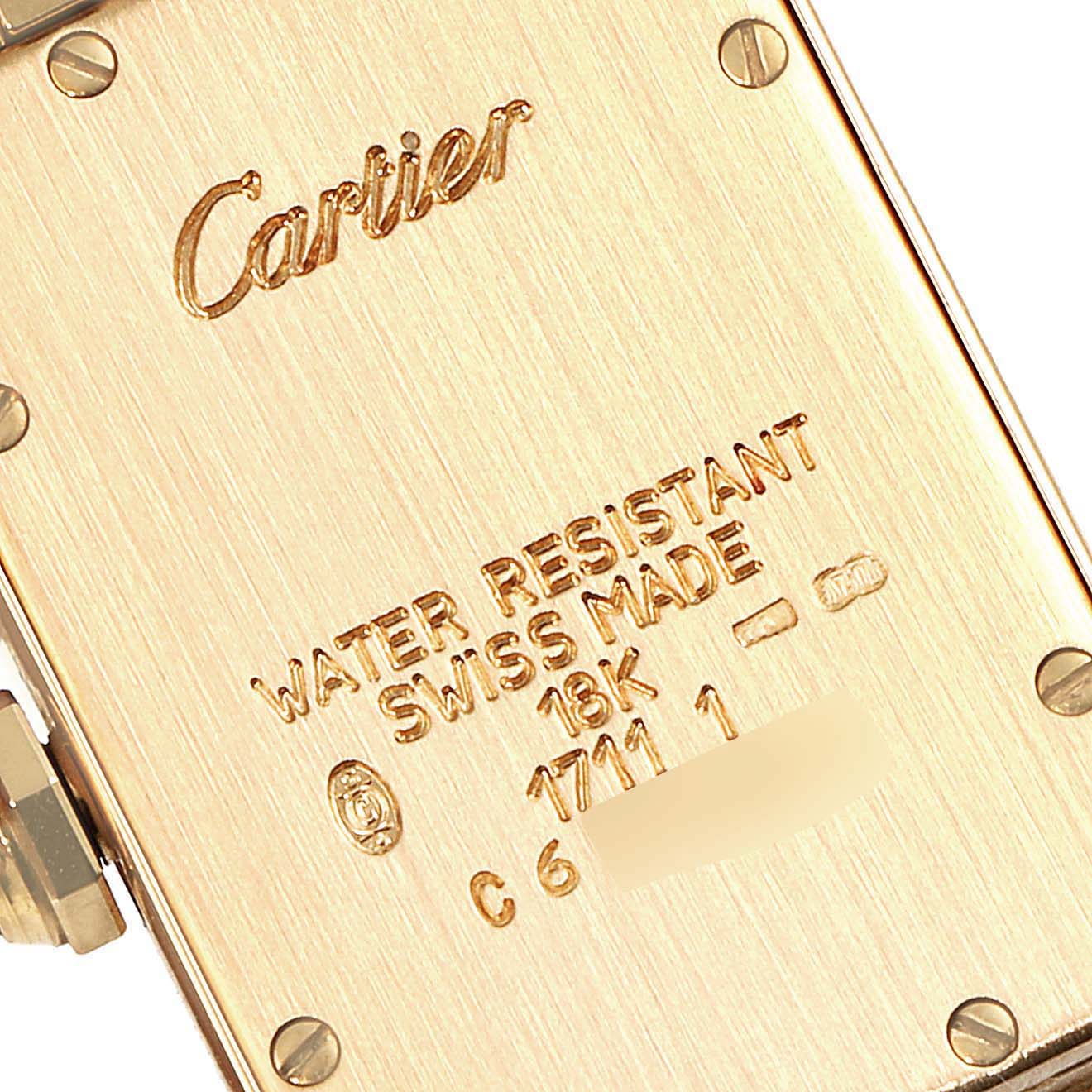 The image shows the back of a Cartier Tank Americaine W26015K2 Women's Yellow Gold Silver Dial W26015K2 Women's Yellow Gold Silver Dial watch at a close-up angle, highlighting its engravings and serial number.