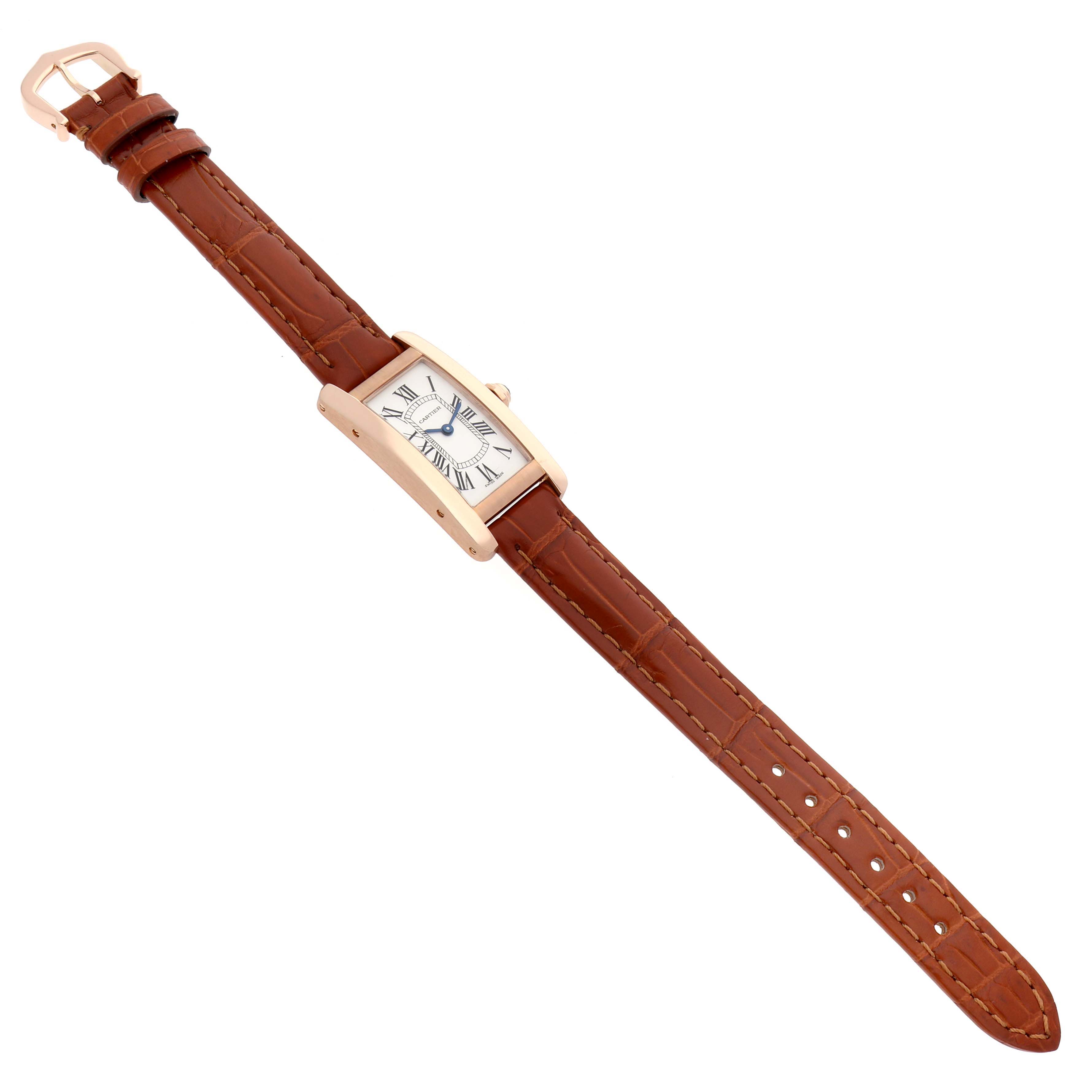 The Cartier Tank Americaine W2607456 Women
s Rose Gold Silver Dial watch is shown at a slight angle, highlighting its rectangular face and brown leather strap.