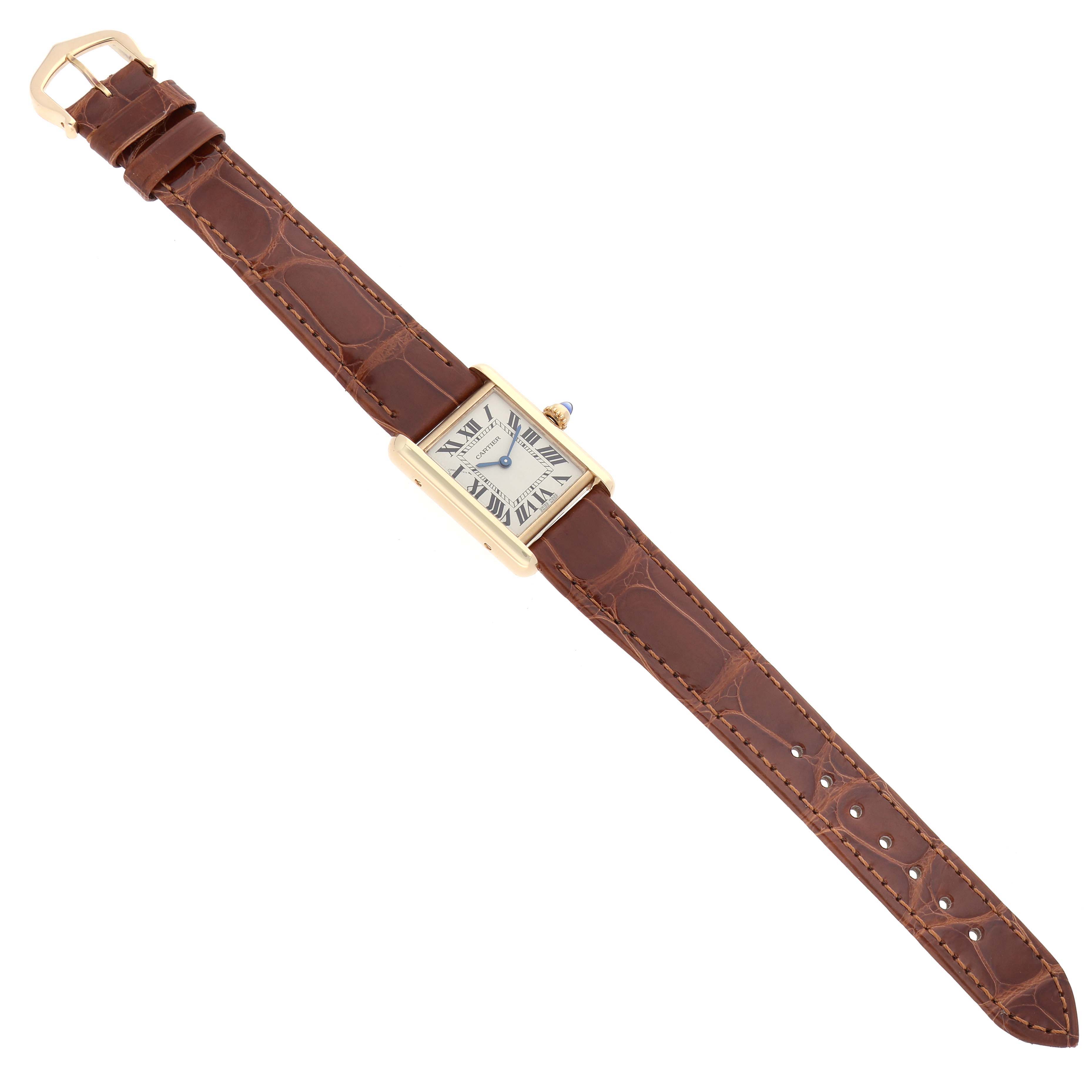 The Cartier Tank Louis W1529856 Women's Yellow Gold Silver Dial watch is shown from a top-down angle, highlighting the rectangular case, Roman numeral dial, and brown leather strap.