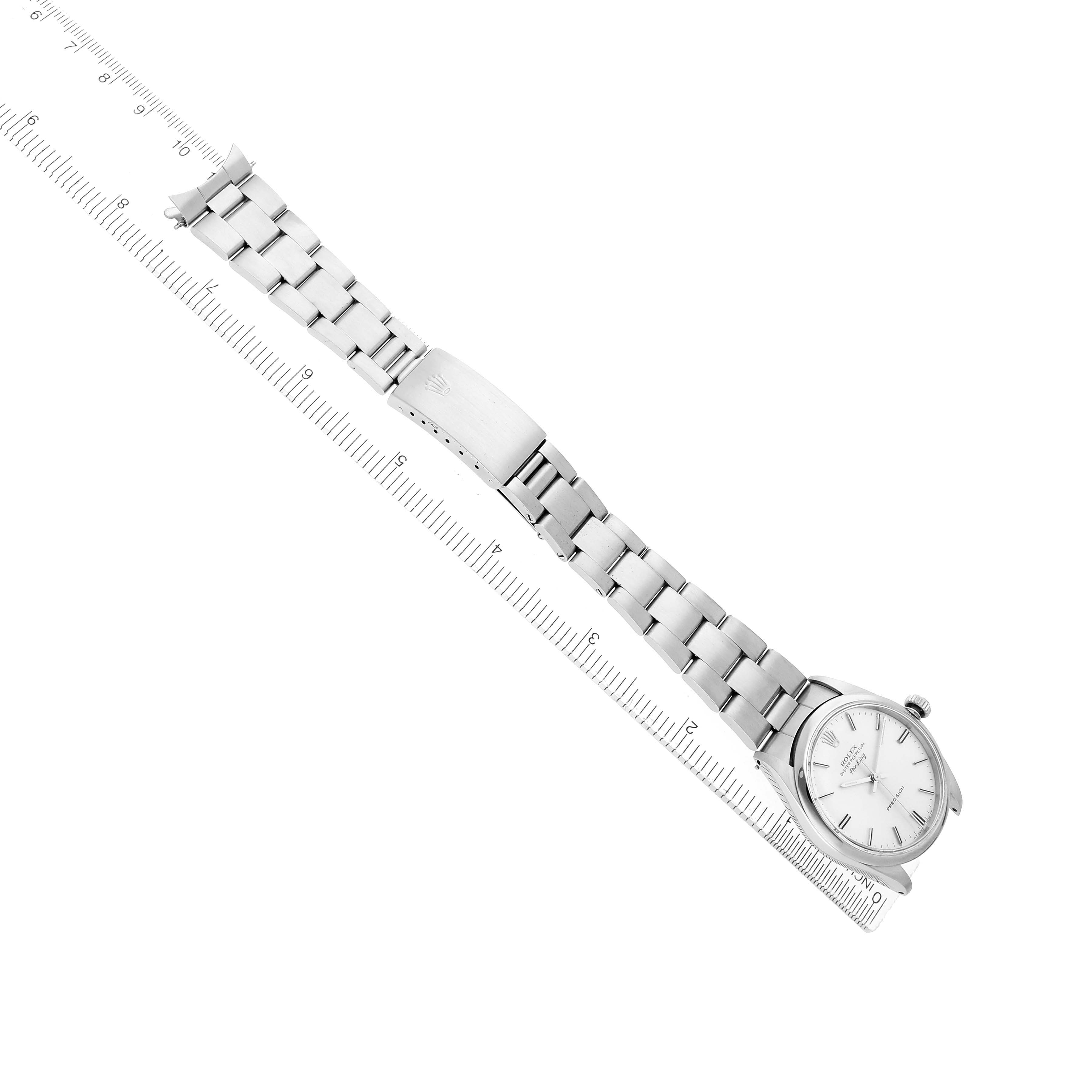 The Rolex Air-King 5500 Men
s Stainless Steel Silver Dial watch is shown at an angled top view, highlighting the bracelet and face alongside a ruler for scale.