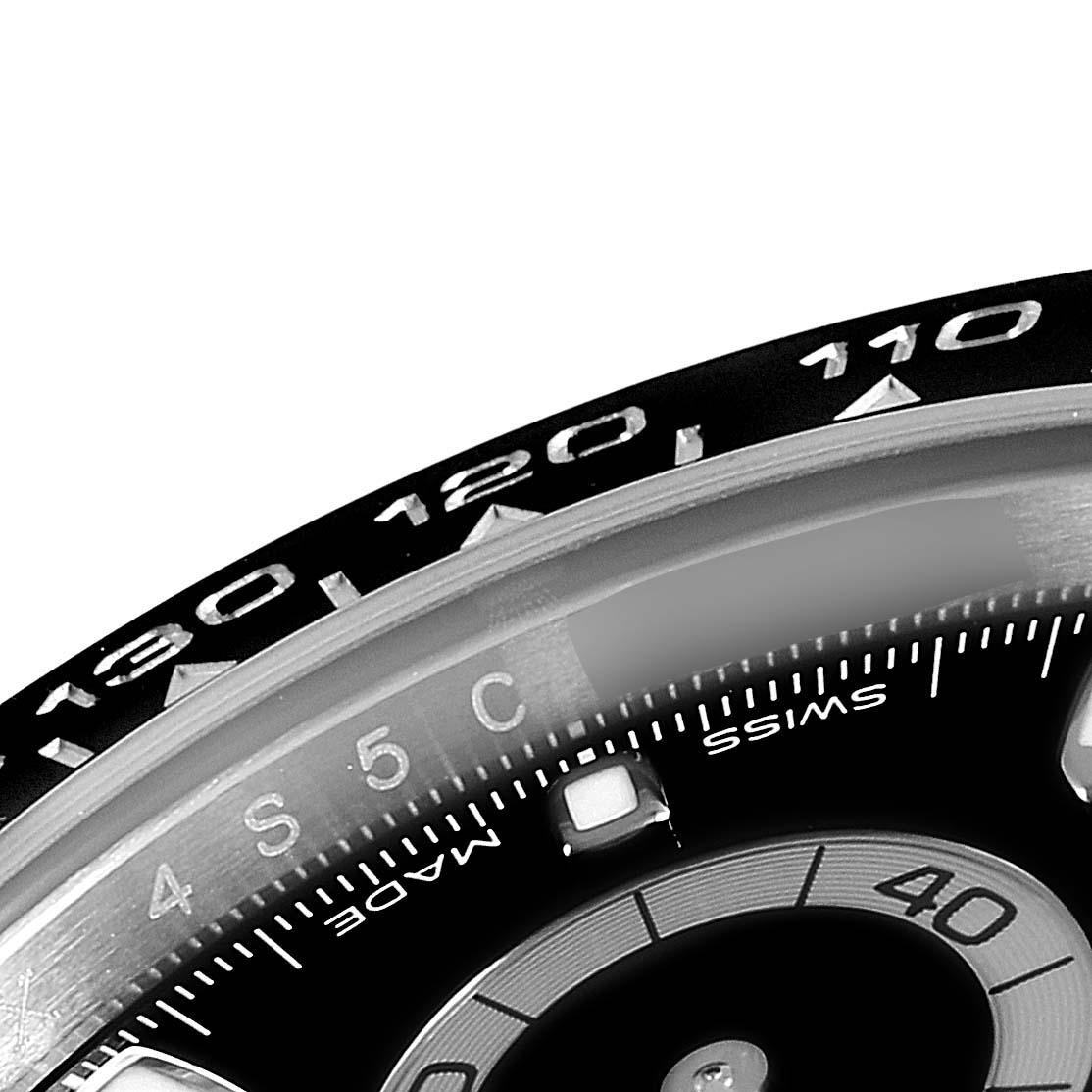 The image shows a close-up of the bezel and dial of a Rolex Daytona 116500 Men's Stainless Steel Black Dial 116500 Men's Stainless Steel Black Dial watch, highlighting the tachymeter scale and markers.